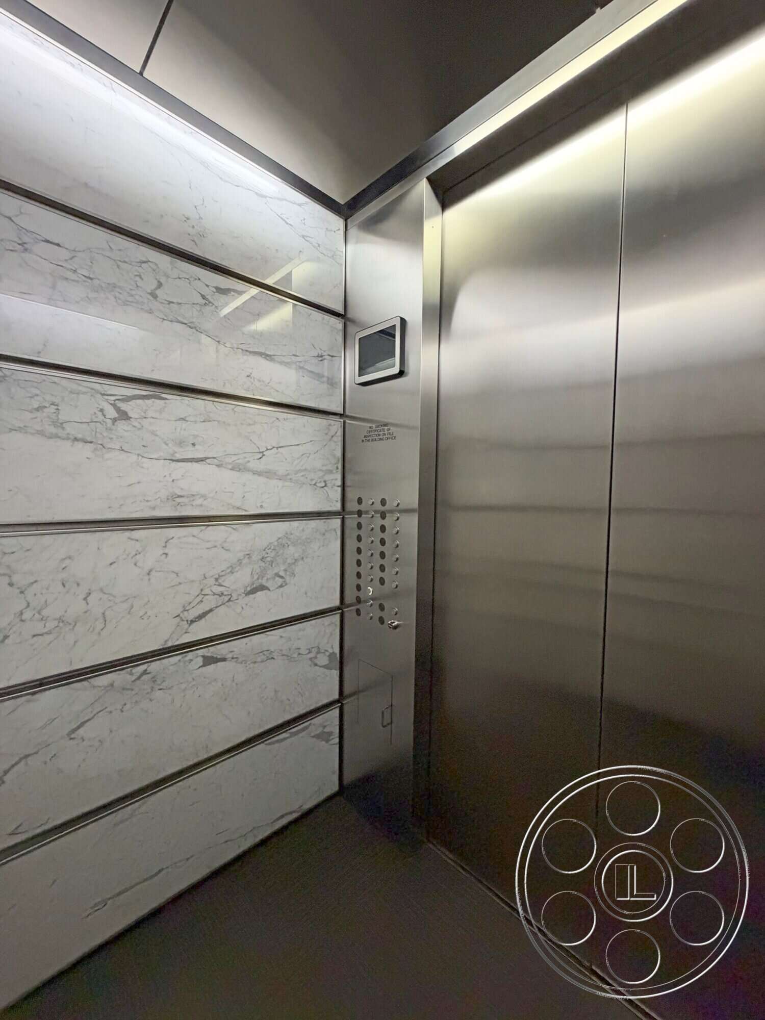 Wilshire Penthouse - soft ambient lighting, black tile flooring, modern minimalist design, textured wall details, stainless steel elevator doors, elevator control panel, interior elevator, marble wall paneling, polished stone finishes