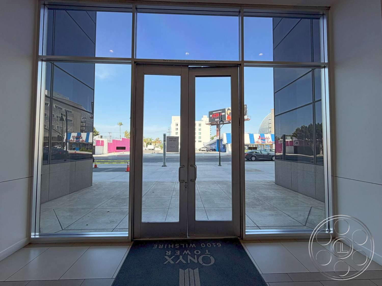Wilshire Penthouse - floor-to-ceiling windows, urban environment, modern architectural style, interior lobby, polished concrete walls, glass entry doors, tile floor entryway, exterior sidewalk, grey granite exterior accents