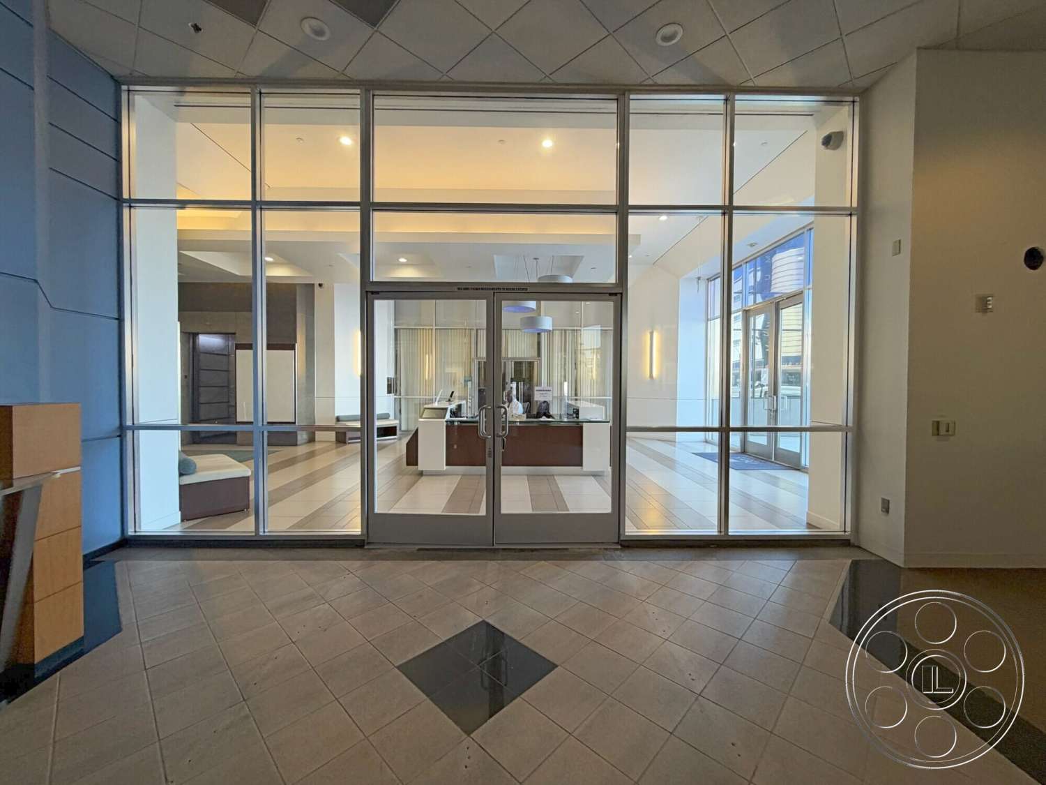 Wilshire Penthouse - neutral color palette, large windows, ceramic tile flooring, exposed ceiling, horizontal wood paneling, linear light fixtures, painted drywall walls, glass entrance doors, modern reception desk, rectangular lobby layout