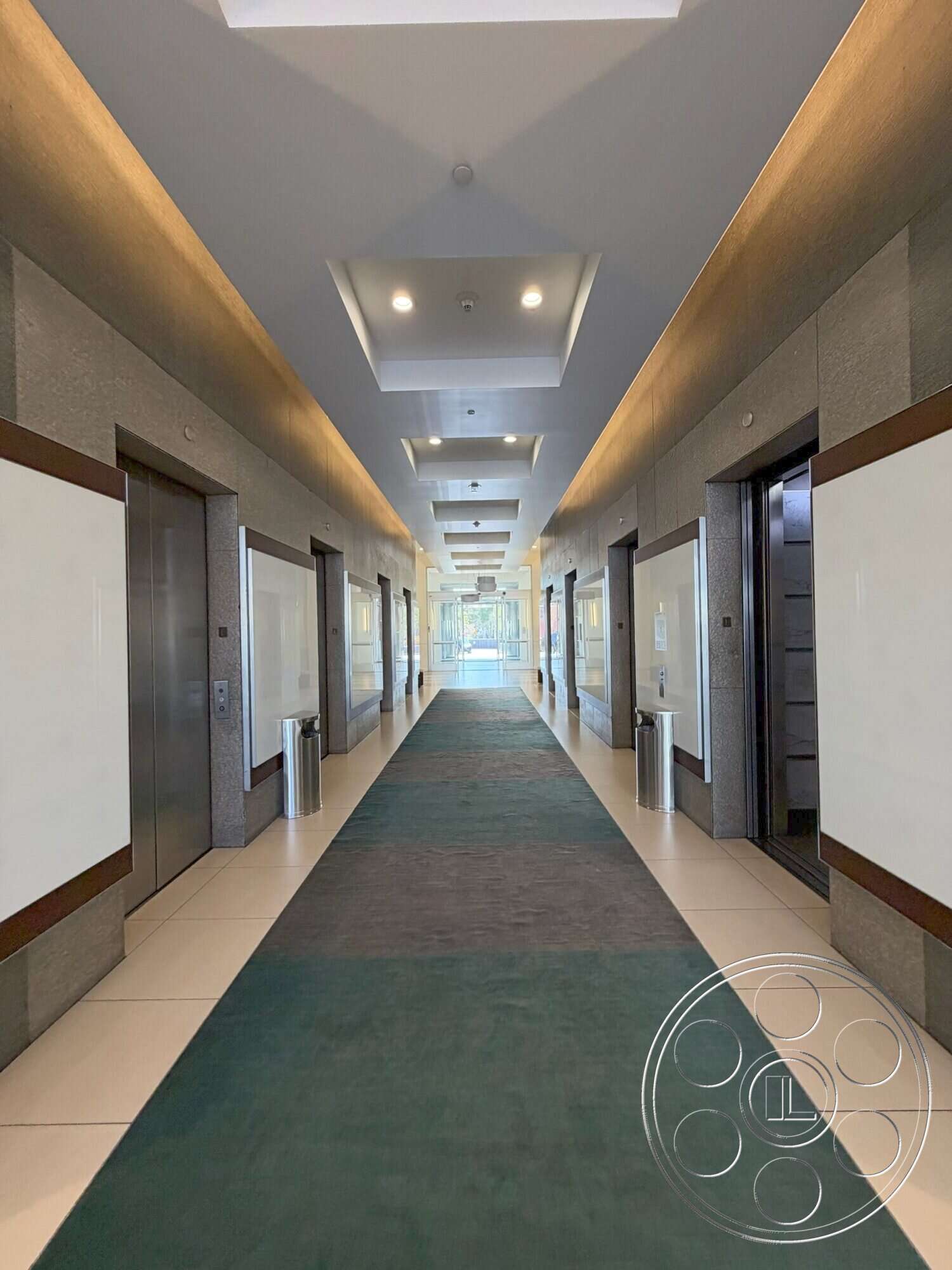 Wilshire Penthouse - neutral color palette, modern lighting fixtures, smooth ceiling, recessed ceiling lights, interior hallway, glass elevator doors, wood trim accents, stone wall panels, carpeted runner, easy-clean tile flooring, open corridor space