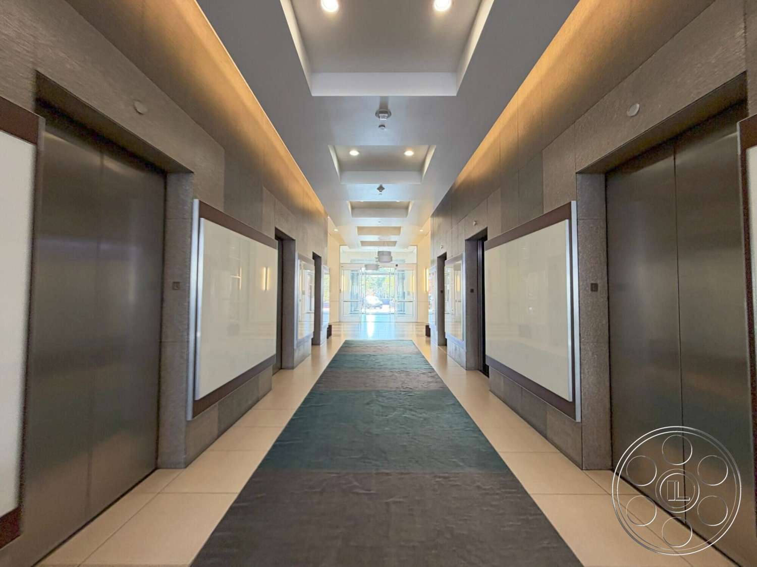 Wilshire Penthouse - textured wall panels, modern architectural style, polished tile flooring, white wall accents, interior hallway, floor-to-ceiling glass windows, ambient ceiling lighting, glass elevator doors, gray carpet runner