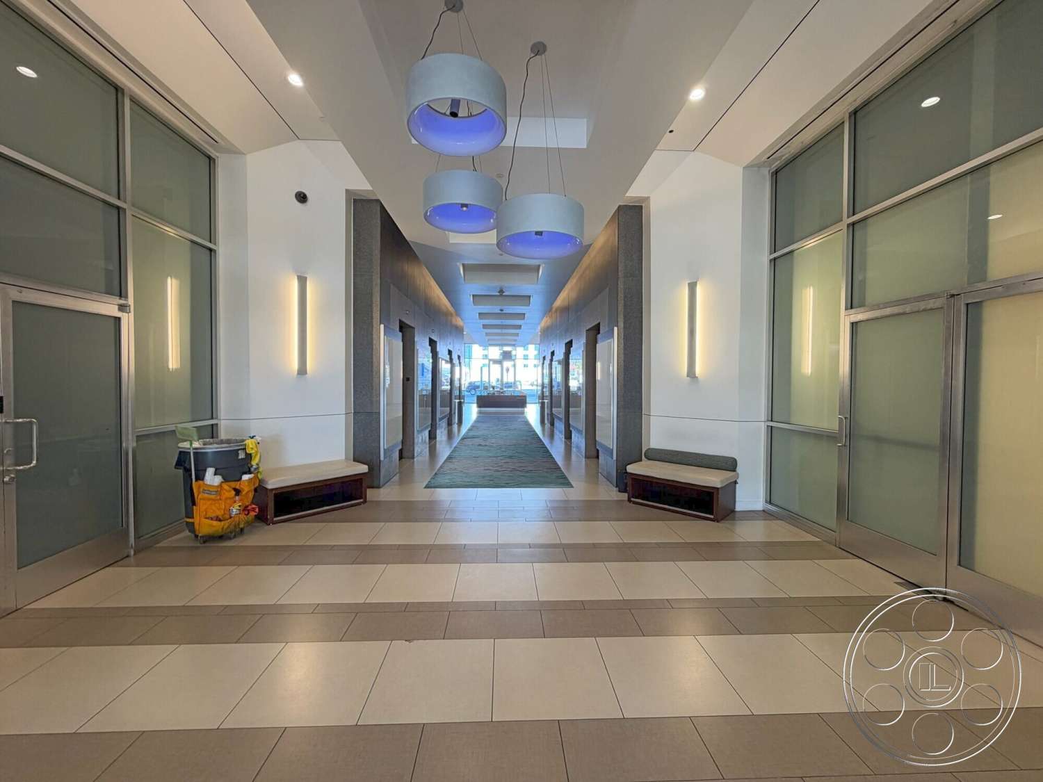 Wilshire Penthouse - neutral color scheme, glass partition walls, recessed lighting fixtures, exposed ceiling lights, clean lines and shapes, modern hanging light fixtures, metal frame doors, polished ceramic tile flooring, gray and white tile patterns, contemporary hallway design, minimalistic benches