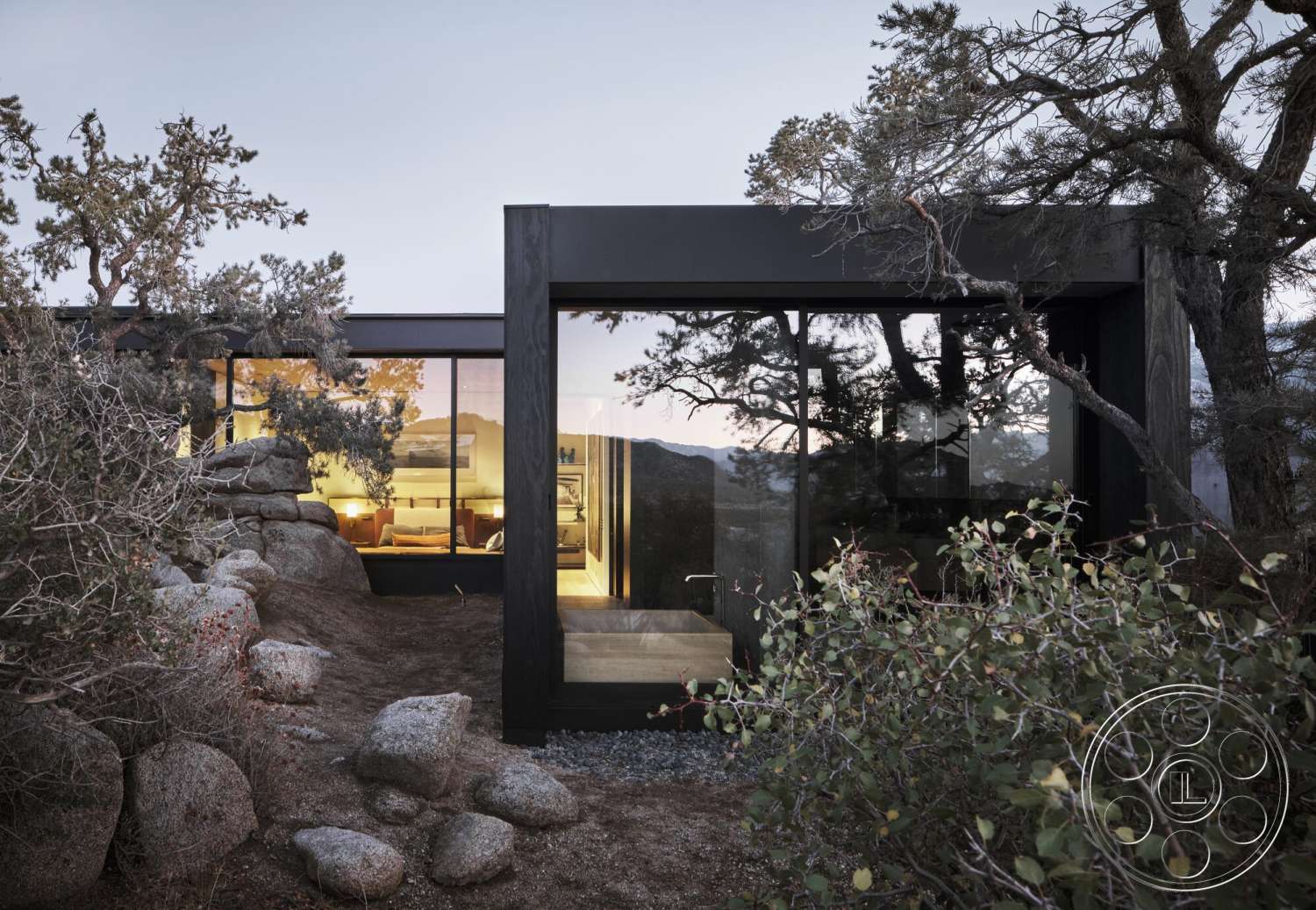Palm Springs 110 - exterior, modern architectural style, horizontal wood siding, flat roof design, mountain view setting, surrounding pine trees, natural stone landscaping, rock garden features, black framed glass walls, integrated outdoor and indoor living