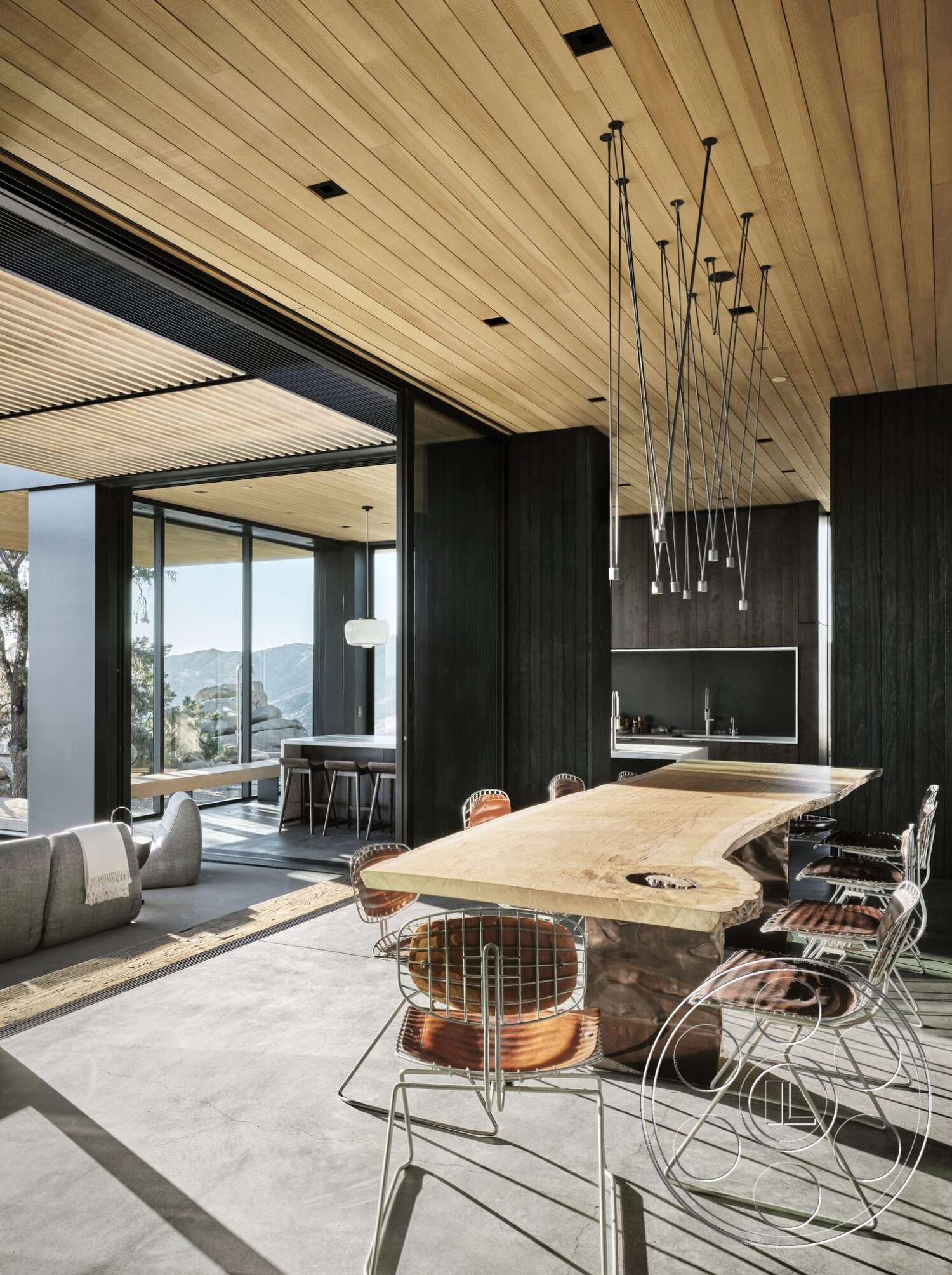 Palm Springs 110 - minimalist design, open floor plan, concrete flooring, floor-to-ceiling windows, natural wood dining table, metal bar stools, wood ceiling panels, modern architectural style, linear pendant lighting, glass wall, black wood cabinetry