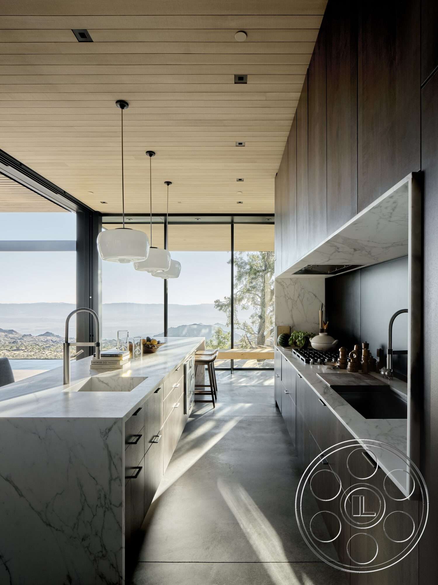 Palm Springs 110 - modern kitchen design, marble kitchen countertop, pendant kitchen lighting, dark wood kitchen cabinets, glass wall with mountain view, concrete kitchen floor, steel kitchen sink, rebate ceiling with wooden slats, high ceiling kitchen design