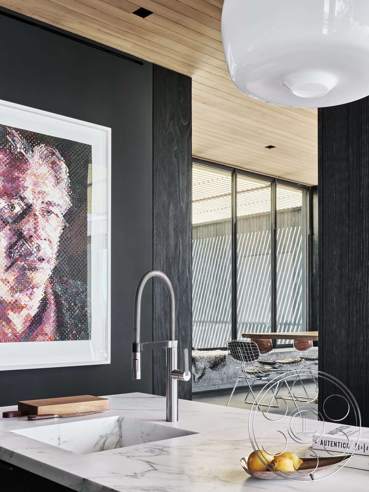 Palm Springs 110 - modern kitchen faucet, black wood paneling, marble kitchen countertop, minimalist dining area, open floor plan layout, stainless steel kitchen sink, artwork featuring vibrant colors, metal wire dining chairs, wood ceiling with linear planks, glass windows with vertical slats