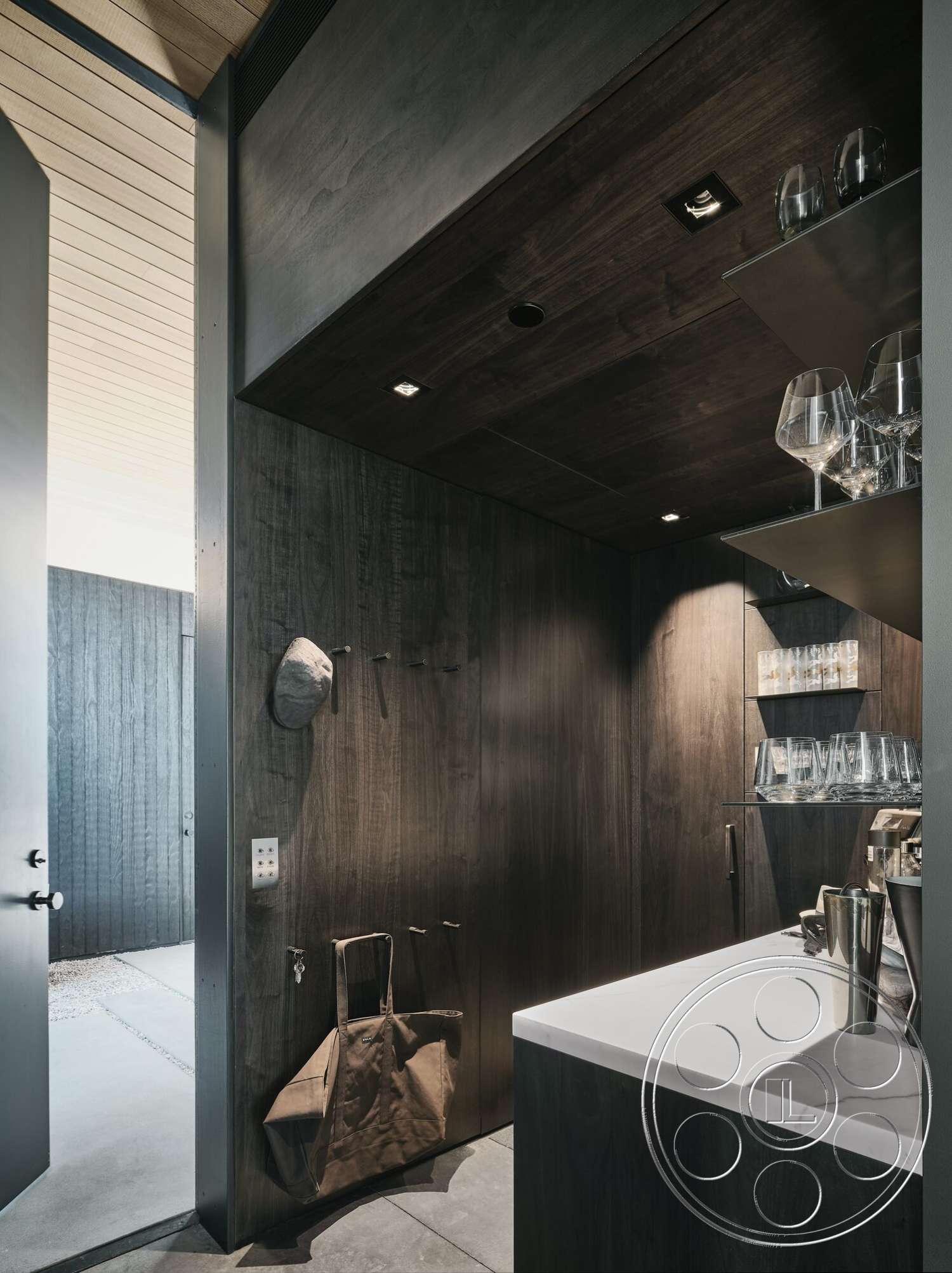 Palm Springs 110 - minimalist design, concrete floor, dark wood paneling, open doorway, textured wood ceiling, white stone countertop, recessed ceiling lighting, glass storage shelves, sleek modern cabinetry, shelving for glassware