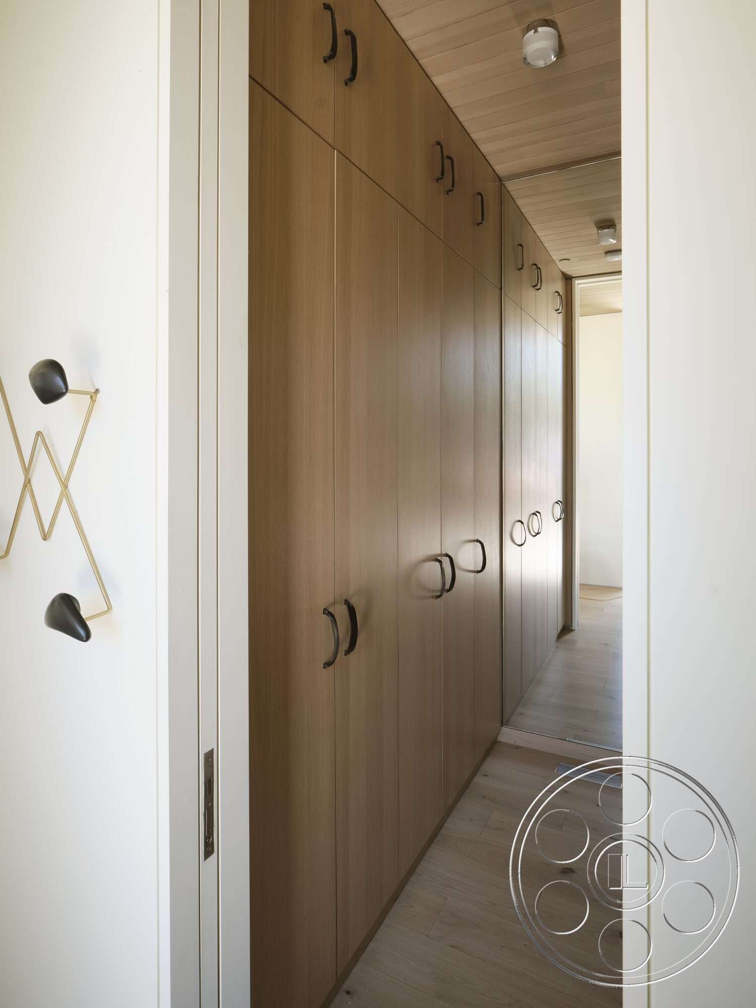 Palm Springs 110 - light wood flooring, wood ceiling panels, minimalist hallway design, wood panel cabinetry, modern interior style, dark hardware handles