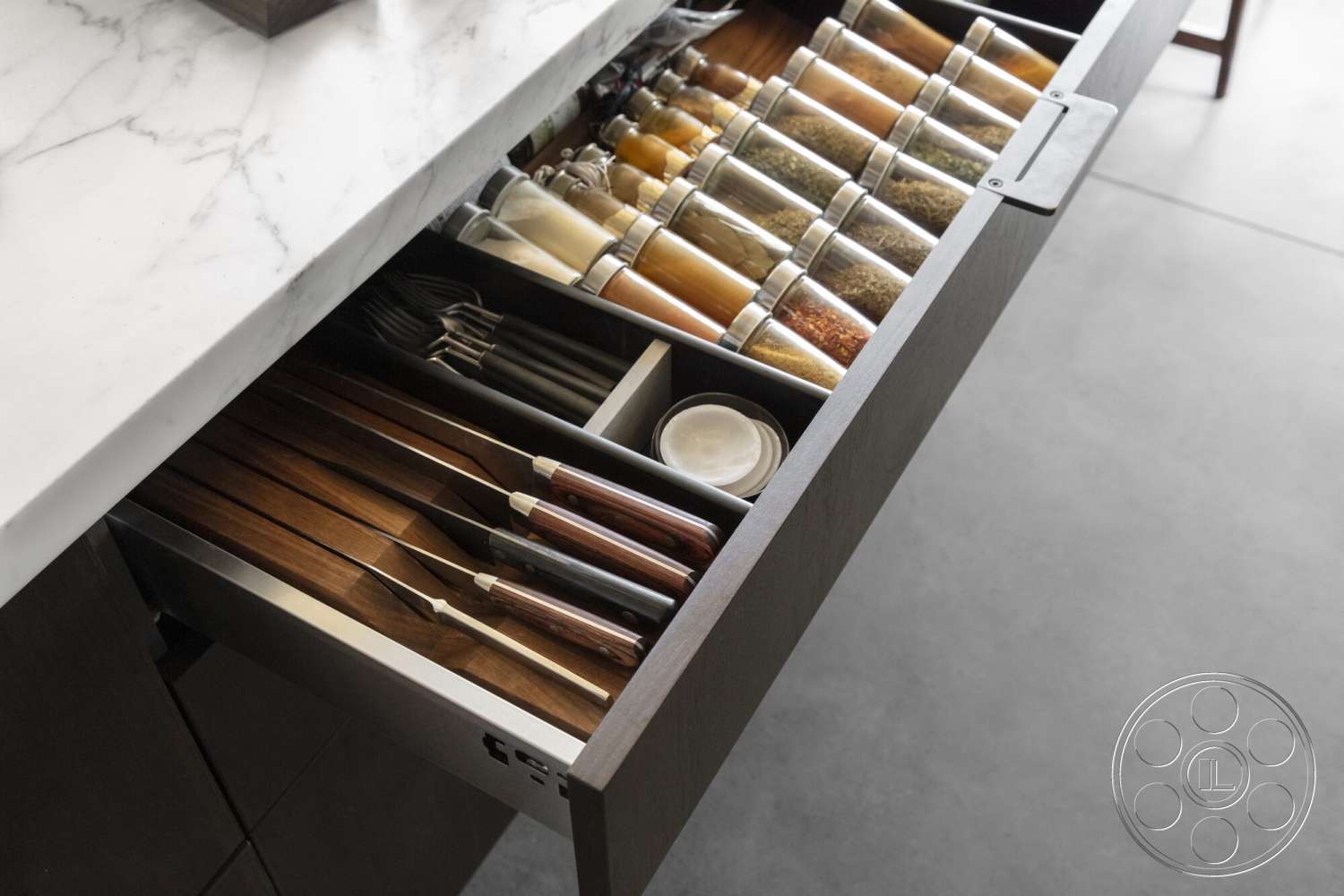 Palm Springs 110 - concrete flooring, marble countertop, dark wood kitchen cabinetry, wooden kitchen utensils, stainless steel drawer pull, glass spice containers, organized kitchen drawer
