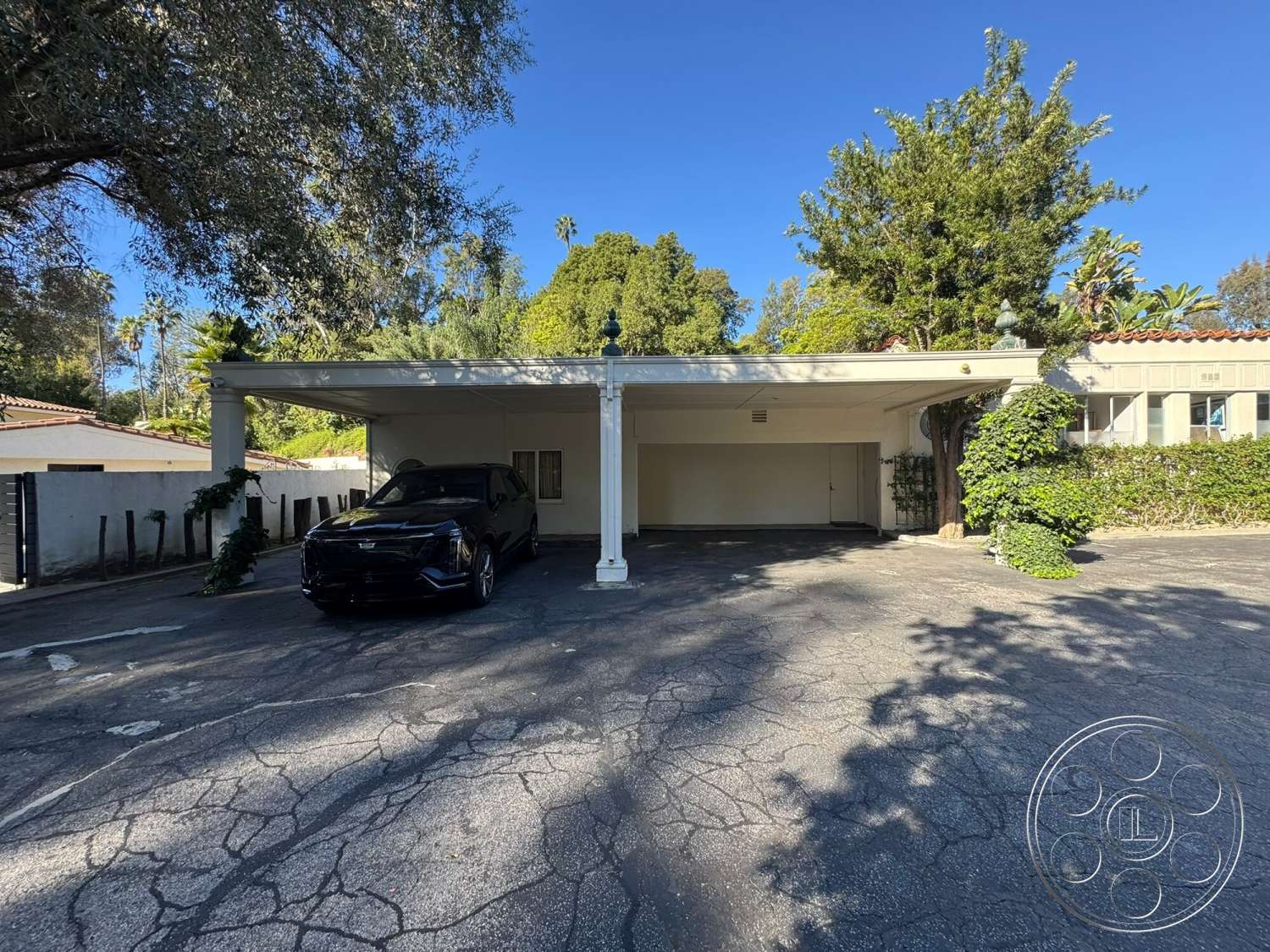 The Hearst House - exterior, landscaped garden, concrete driveway, trees providing shade, wooden support beams, paved parking area, flat roof carport, modern carport design, leafy green surroundings, detailed architectural features, tiled roof accent