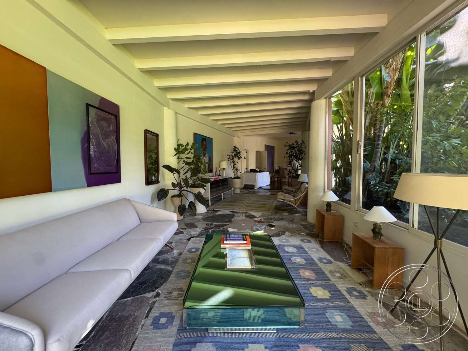 The Hearst House - textured area rug, minimalist design elements, glass sliding doors, slate flooring, modern coffee table, floor-to-ceiling windows, wooden side tables, open concept living space, decorative houseplants, exposed wood ceiling beams, natural light streaming in, framed artwork on walls, contemporary sofa, colorful accent walls
