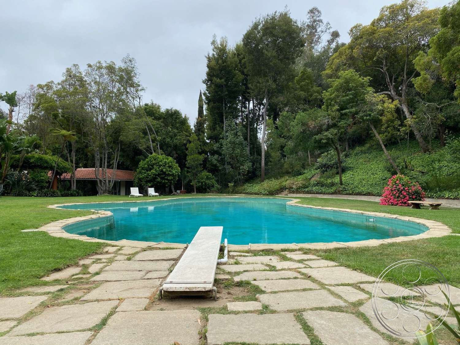The Hearst House - exterior, surrounding trees, stone pathway, tropical landscaping, rectangular pool, outdoor relaxation space, swimming pool area, lush garden setting, stone patio flooring, concrete pool border, grassy lawn area