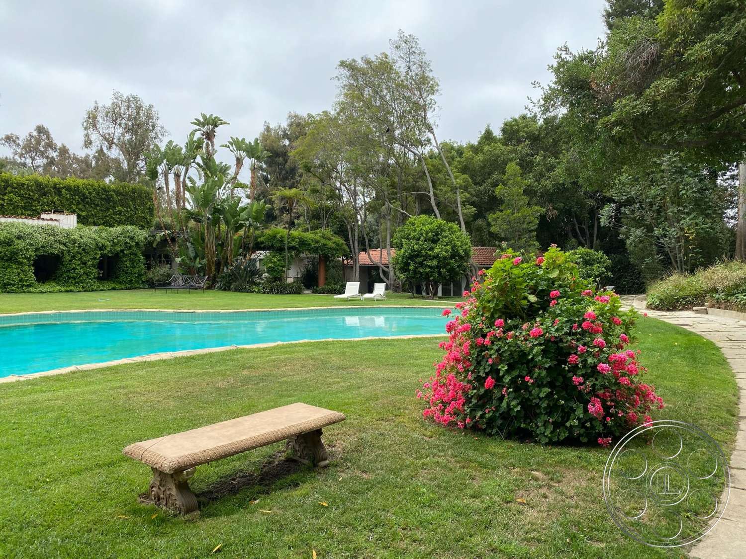 The Hearst House - rectangular swimming pool, grass lawn, tropical landscaping, outdoor pool area, benched seating, flowering shrubbery, stone patio flooring, concrete pool border, exterior garden setting, residential home environment