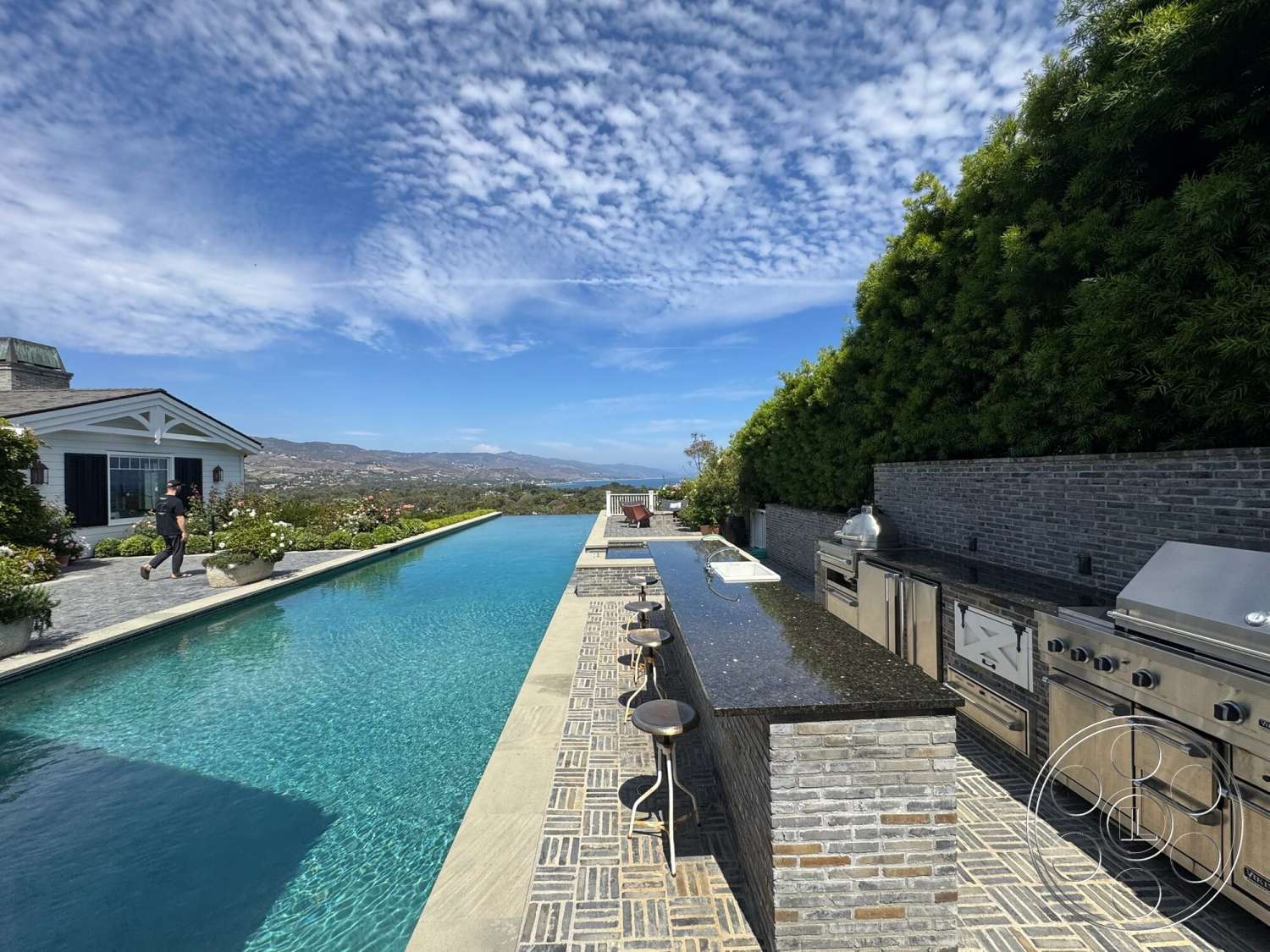 Americana 113 - exterior, landscaped garden, stone wall, mountain view, infinity pool, concrete pool deck, outdoor entertainment area, cobblestone patio flooring, stainless steel outdoor kitchen appliances, granite outdoor kitchen countertops, rectangular outdoor bar area