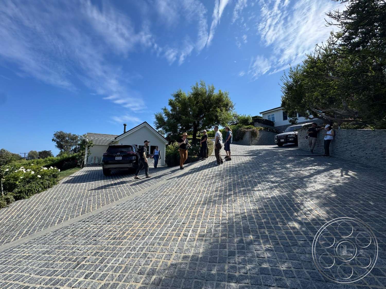 Americana 113 - natural light, exterior, landscaped garden, modern architecture, single-story home, blue sky, sloped driveway, wooden fence, cobblestone driveway, bushes and trees