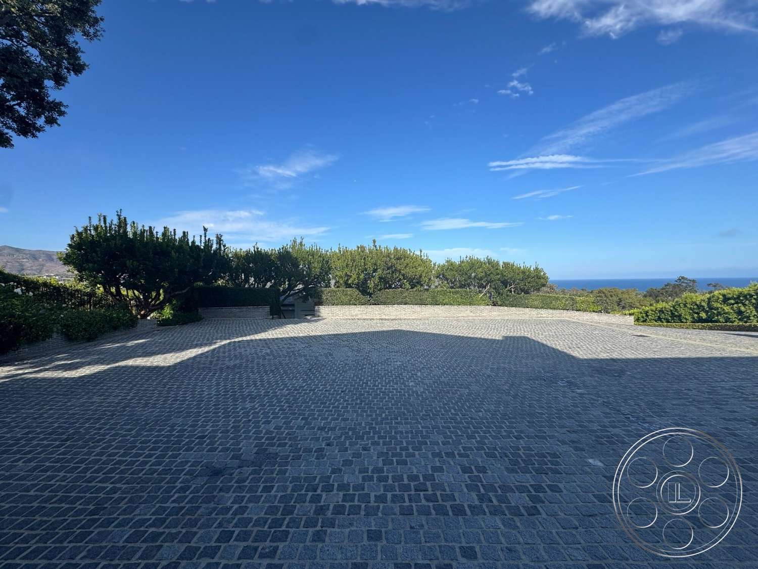 Americana 113 - exterior, landscaped garden, ocean view, suburban backyard, well-maintained greenery, cobblestone driveway, terraced landscaping, sunny outdoor setting