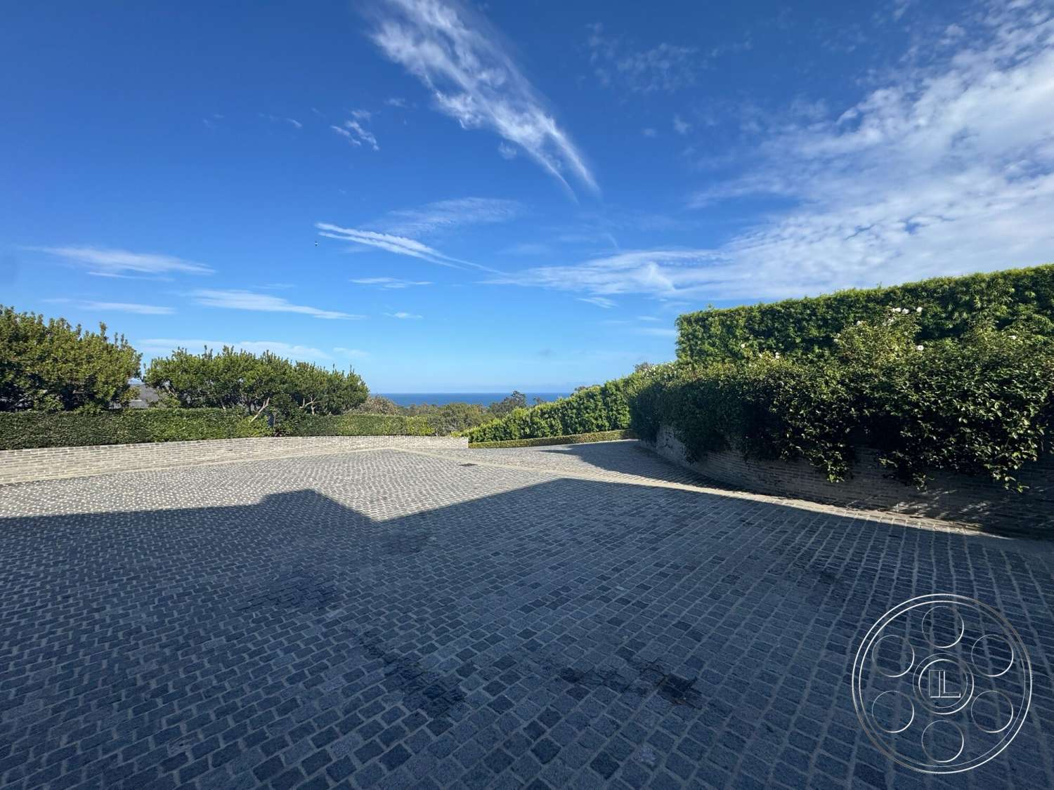 Americana 113 - exterior, ocean view, cobblestone driveway, hedge landscaping, flat terrain, skyline with clouds
