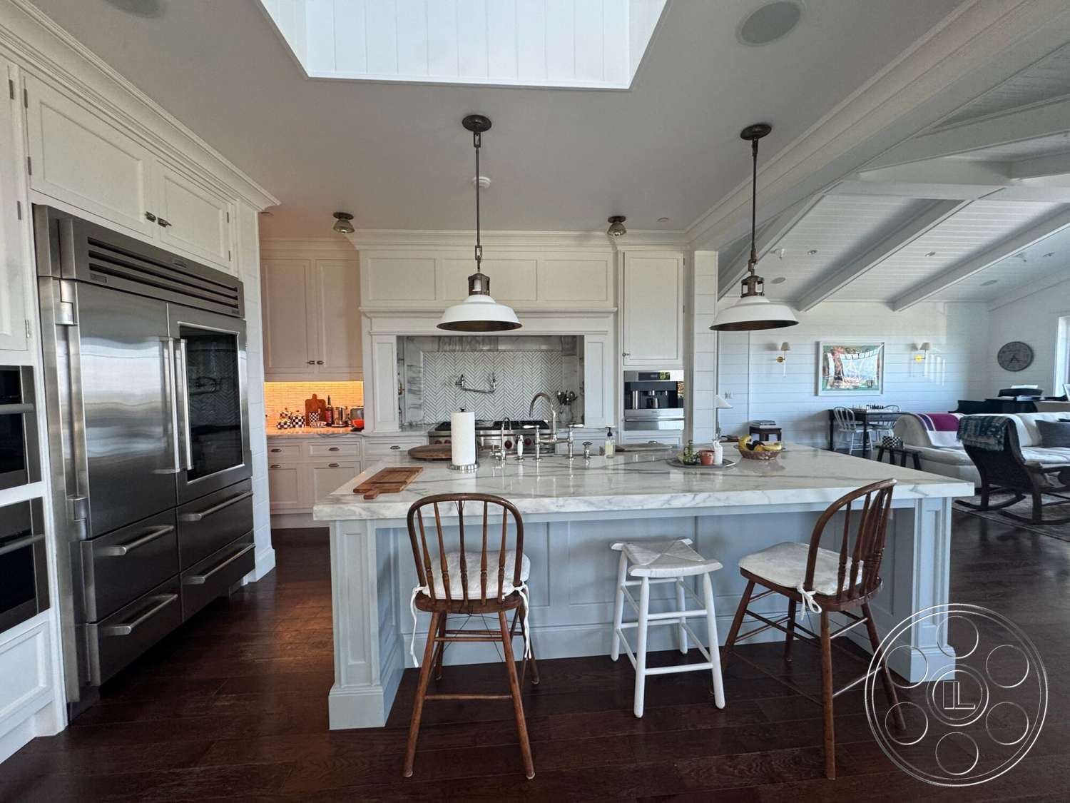 Americana 113 - subway tile backsplash, modern pendant lighting, decorative wall art, comfortable seating area, stainless steel refrigerator, dark hardwood kitchen floors, open concept kitchen, marble kitchen countertop, white shaker cabinetry, chefs kitchen, light wood island base, vaulted ceiling with white wood beams, herringbone tile detail