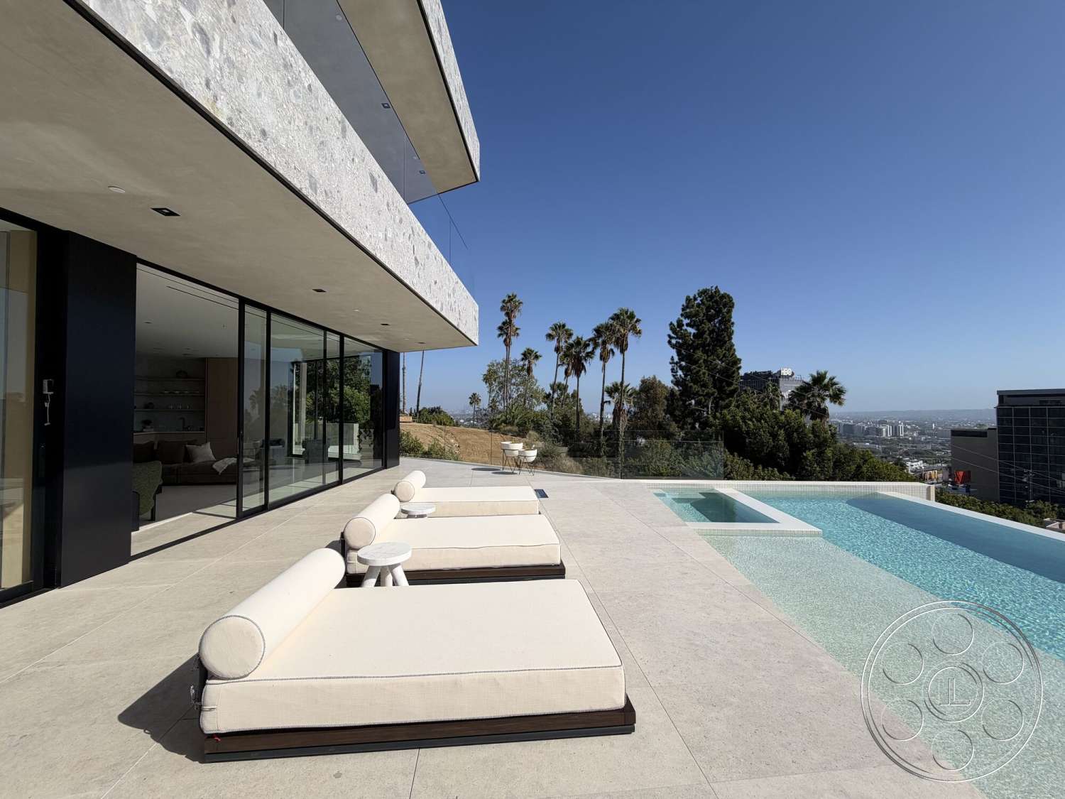 Modern 532 - exterior, glass sliding doors, rectangular swimming pool, modern architectural style, lounge chairs, city skyline view, infinity pool, concrete pool deck, concrete patio flooring, landscaped hillside setting, stone facade walls, contemporary outdoor area