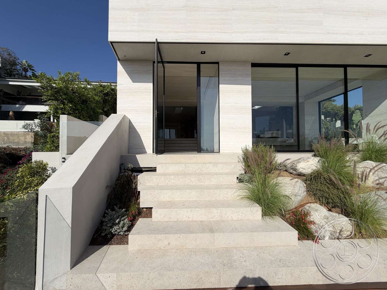 Modern 532 - exterior, concrete steps, large floor-to-ceiling windows, open foyer, landscaped garden beds, natural stone boulders, modern minimalist architecture, glass entrance doors, horizontal wood panel siding, stone landing