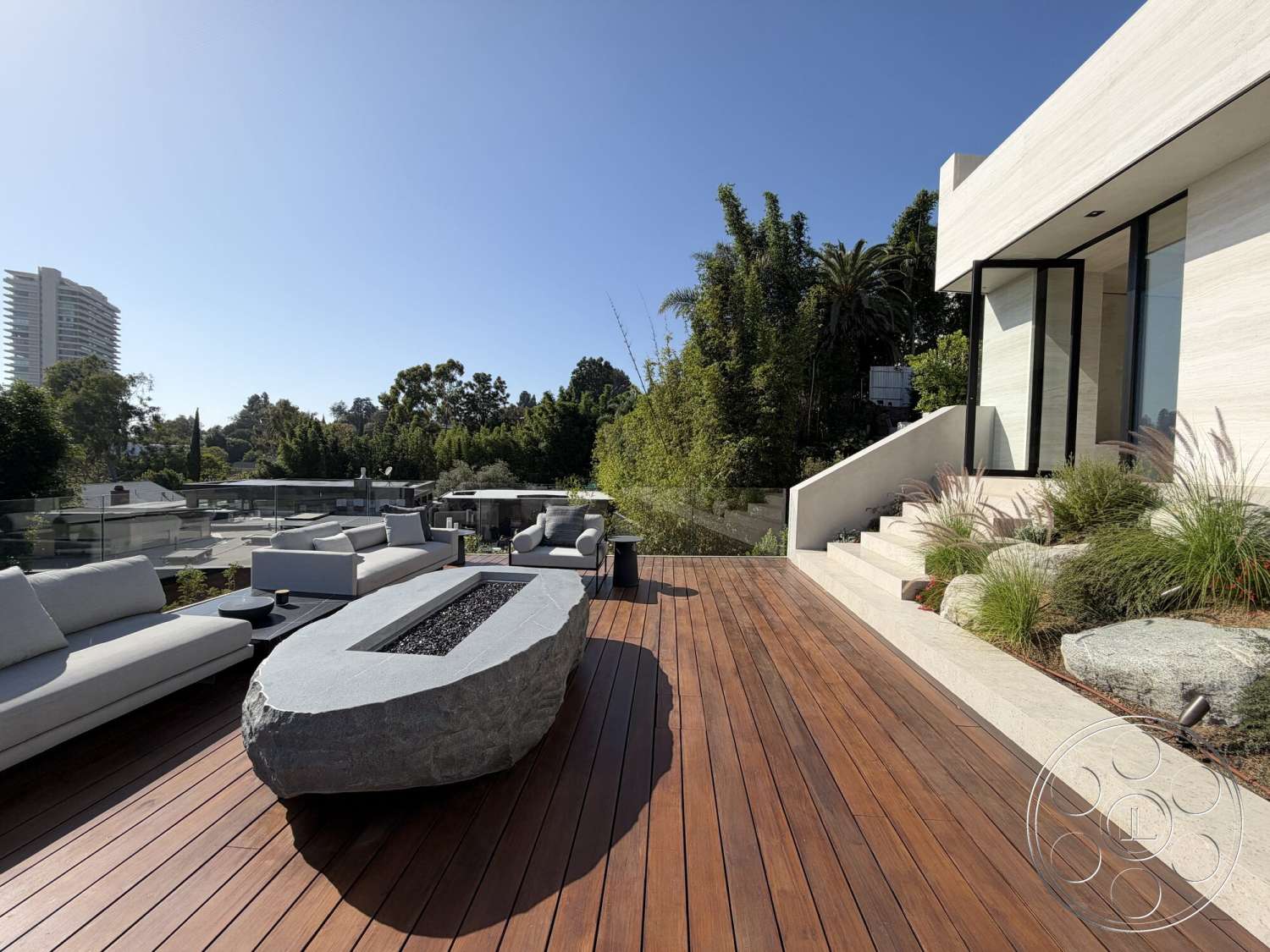 Modern 532 - exterior, glass railing, concrete steps, wood deck, modern outdoor seating, horizontal wood siding, contemporary home facade, lush greenery landscaping, textured stone fire pit, integrated garden elements