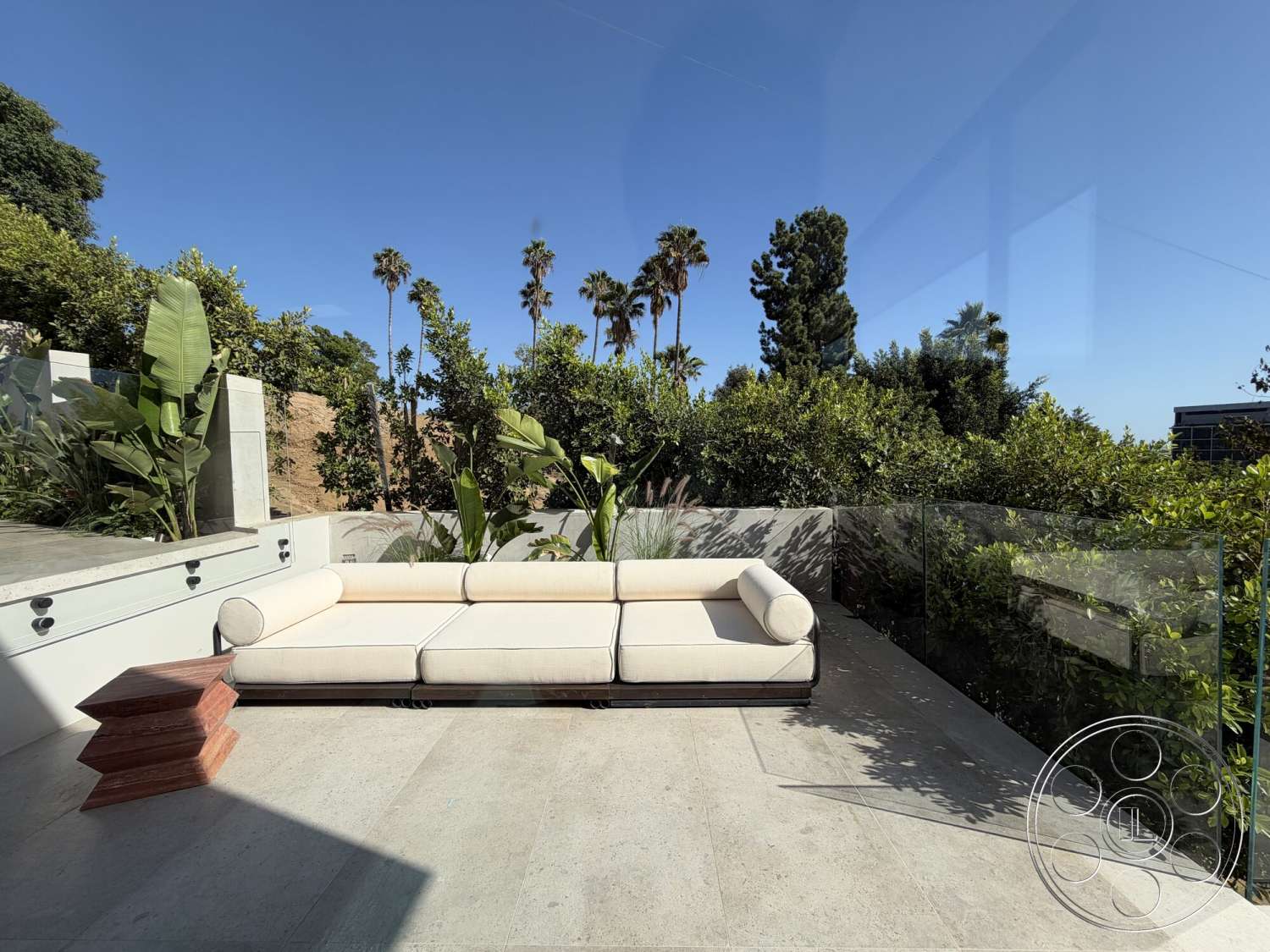 Modern 532 - exterior, minimalist design, glass railing, tropical plants, sunny outdoor space, modern outdoor seating, wood accent table, concrete patio flooring, landscaped garden setting, rectangular seating arrangement