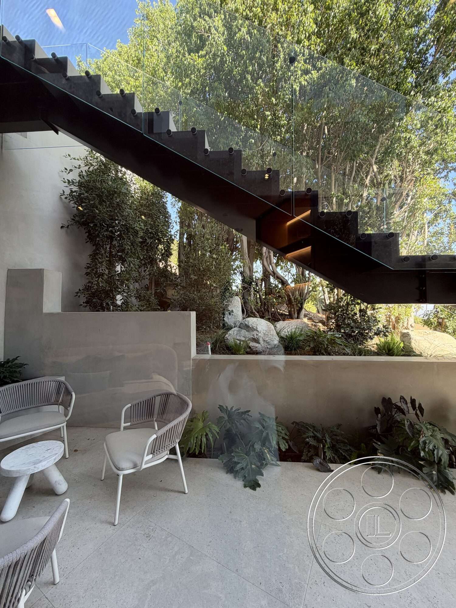 Modern 532 - exterior, lush greenery, textured plaster wall, urban garden setting, outdoor lounge area with modern chairs, concrete landscaping walls, natural stone garden planters, modern glass balcony railing, metal staircase with glass treads, hardscape patio flooring