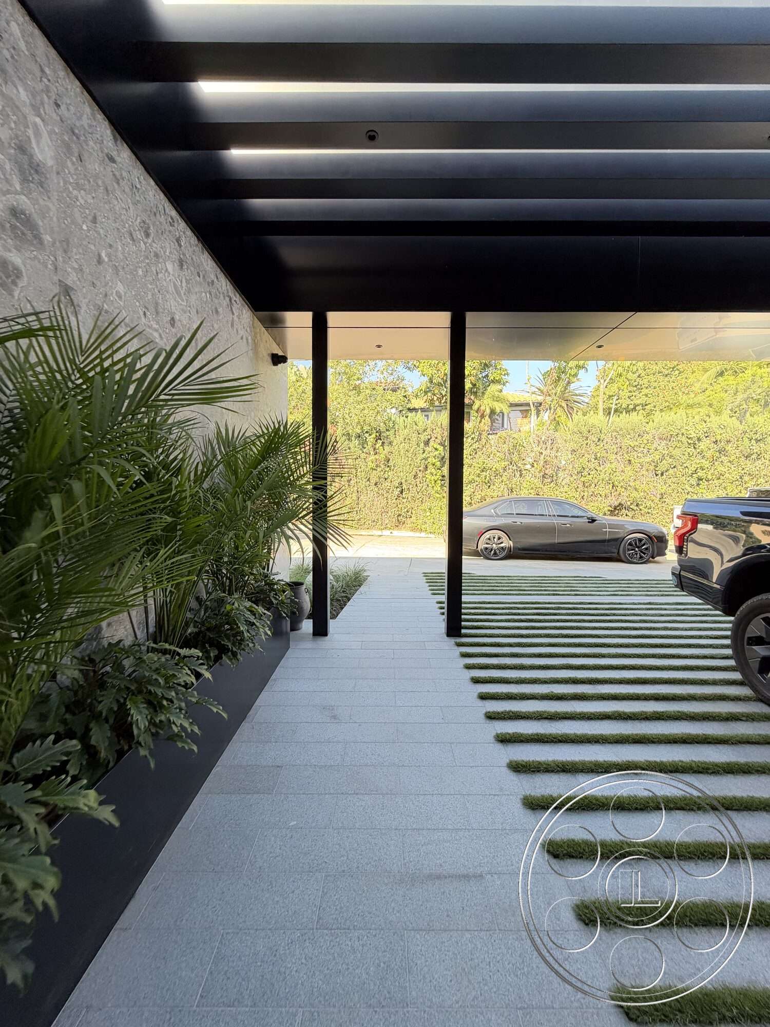 Modern 532 - exterior, modern architectural style, landscape plants, concrete walkway, asphalt driveway, horizontal wood slat roof overhang, striped grass accents, gray stone wall cladding