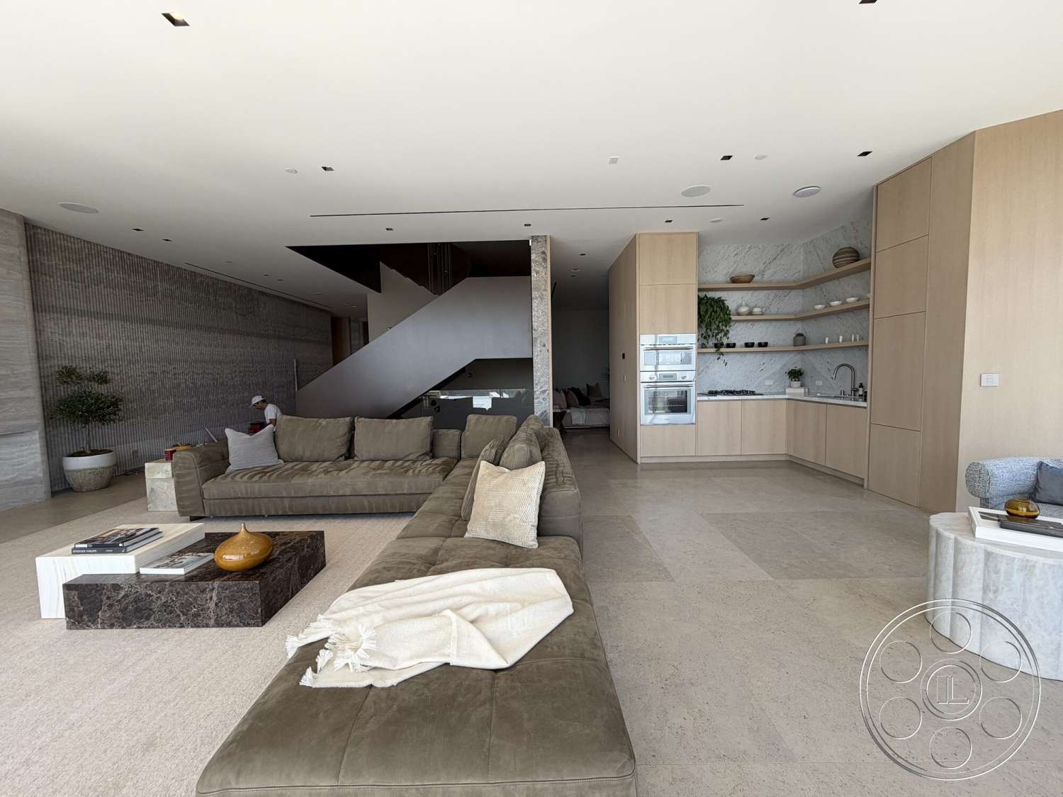Modern 532 - minimalist decor, woven throw blanket, light wood cabinetry, stone coffee table, contemporary bar stools, large sectional sofa, floating staircase, marble kitchen countertops, open concept living area, ambient recessed lighting, textured concrete accent wall, green indoor plant feature, modern decorative accents, stone floor tiles