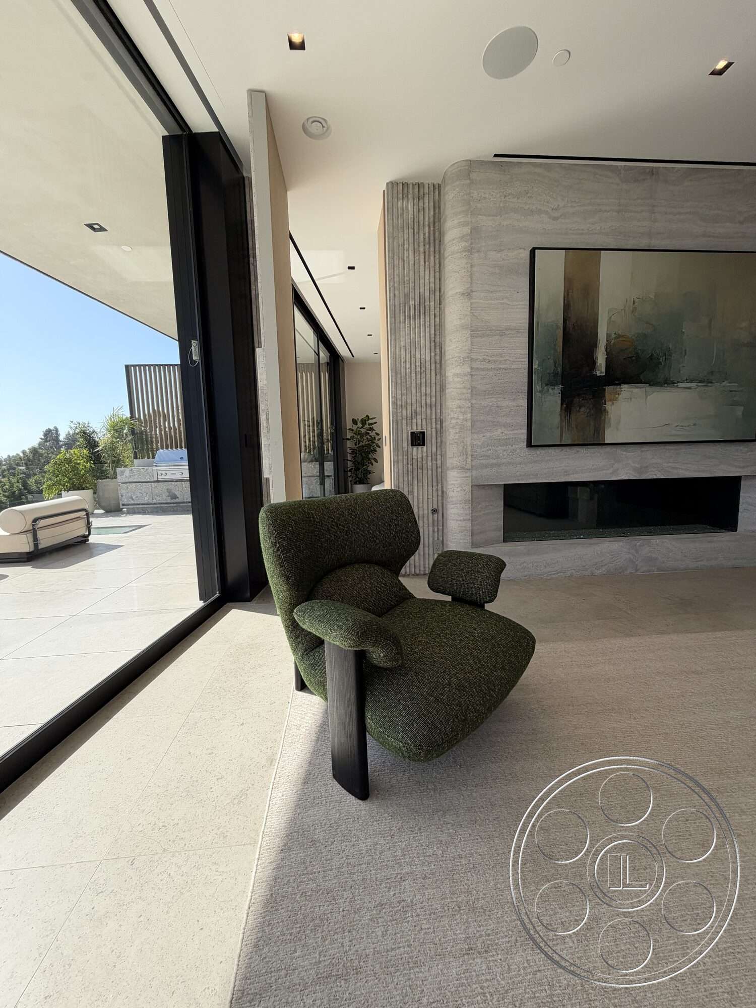 Modern 532 - minimalist decor, open floor plan, floor-to-ceiling windows, soft area rug, mountain view, textured plaster walls, luxury residence, light-colored stone flooring, contemporary art piece, modern fireplace design, plush green upholstered armchair, black wooden chair legs, natural light intrusion, vertical wooden slat partition