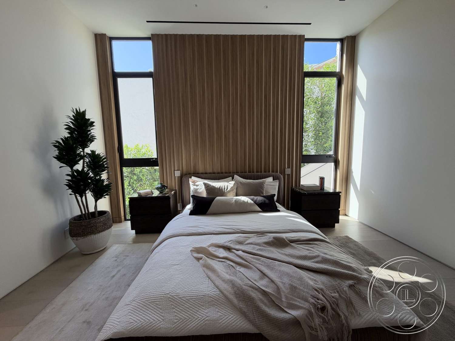 Modern 532 - neutral color palette, textured area rug, floor-to-ceiling windows, soft window treatments, light-filled space, hardwood bedroom floors, wood paneling accent wall, plush bedding with decorative pillows, large potted plant, modern bedside tables