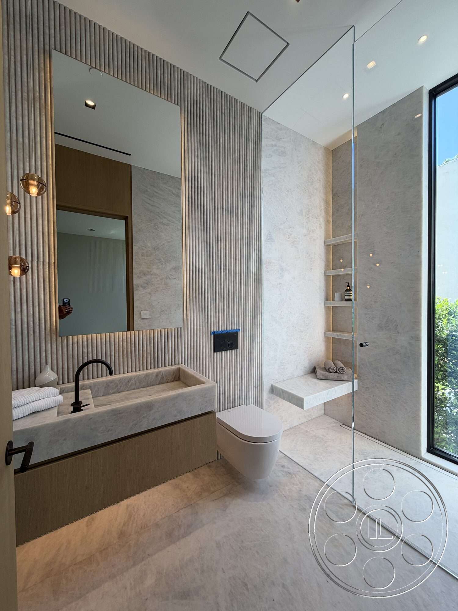 Modern 532 - minimalist design, glass shower enclosure, rectangular mirror, contemporary bathroom, metal wall sconces, textured plaster wall treatment, marble bathroom flooring, marble bathroom walls, modern toilet, large floor-to-ceiling window, floating wood shelf, vanity with marble countertop, ribbed wood cabinetry