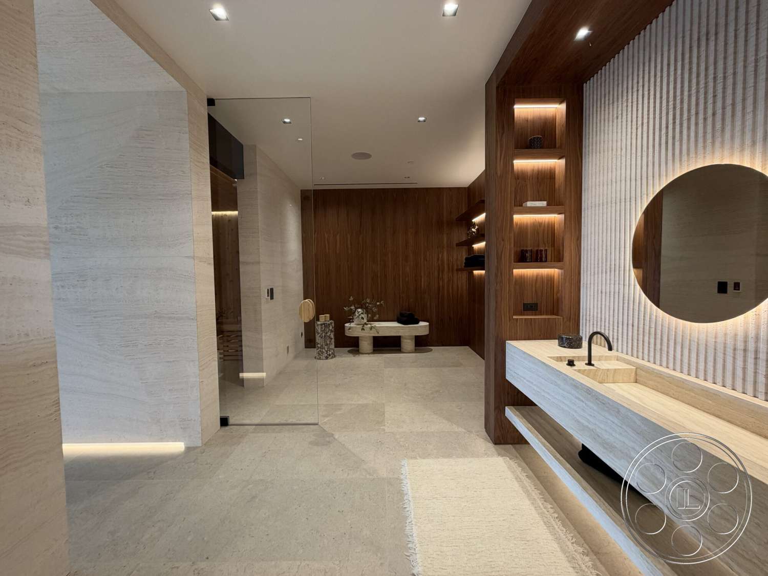 Modern 532 - textured plaster walls, under-mounted sink, modern bathroom design, wood panel accent wall, decorative stone feature, travertine flooring, integrated lighting details, fixed glass partition wall, minimalist floating vanity, round mirror with backlighting, open shelf display