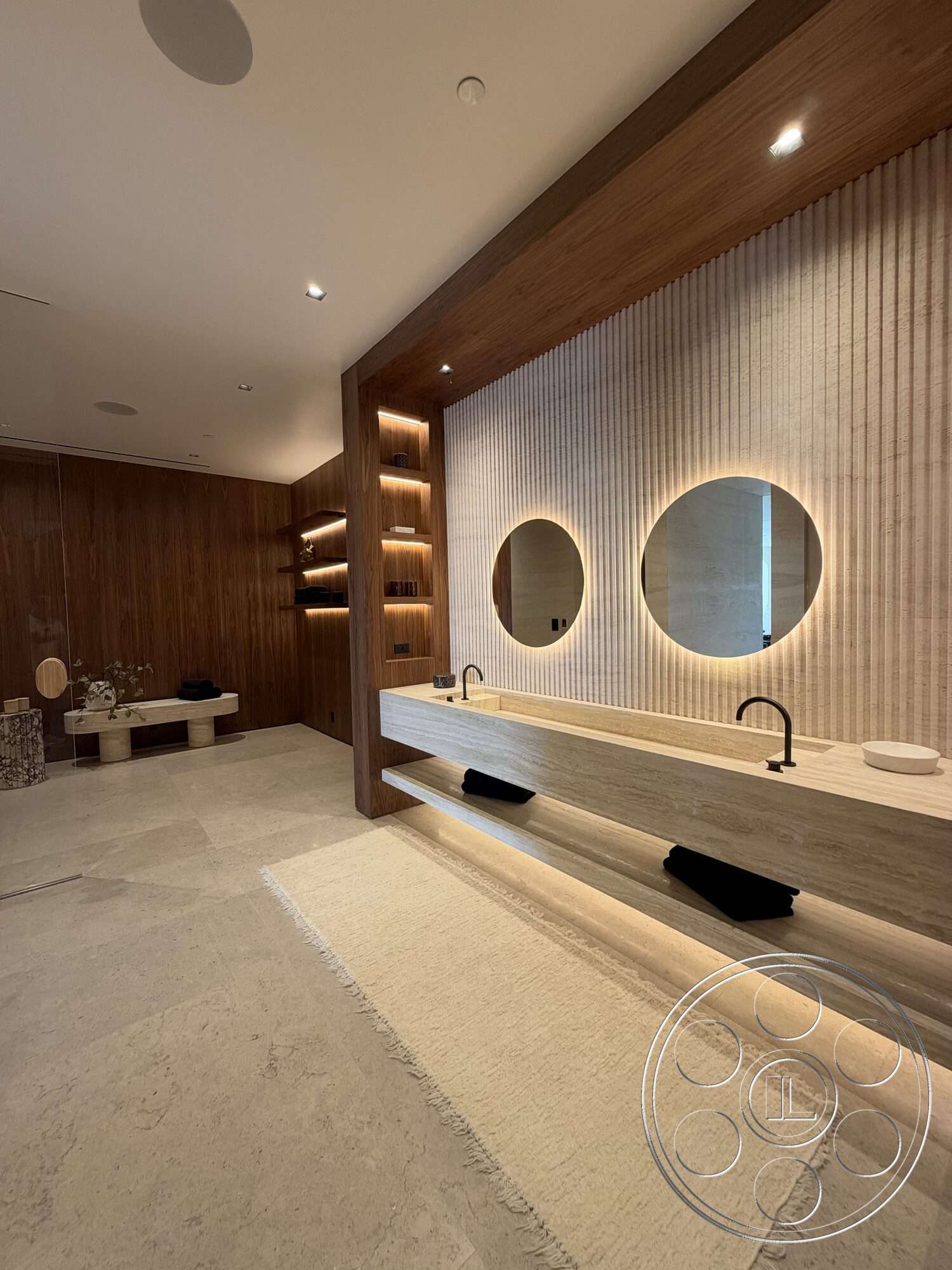 Modern 532 - soft area rug, recessed lighting fixtures, textured plaster wall, contemporary design aesthetic, wood paneling wall, honed stone countertop, round mirrors with backlighting, floating vanity with built-in storage, neutral-colored stone flooring