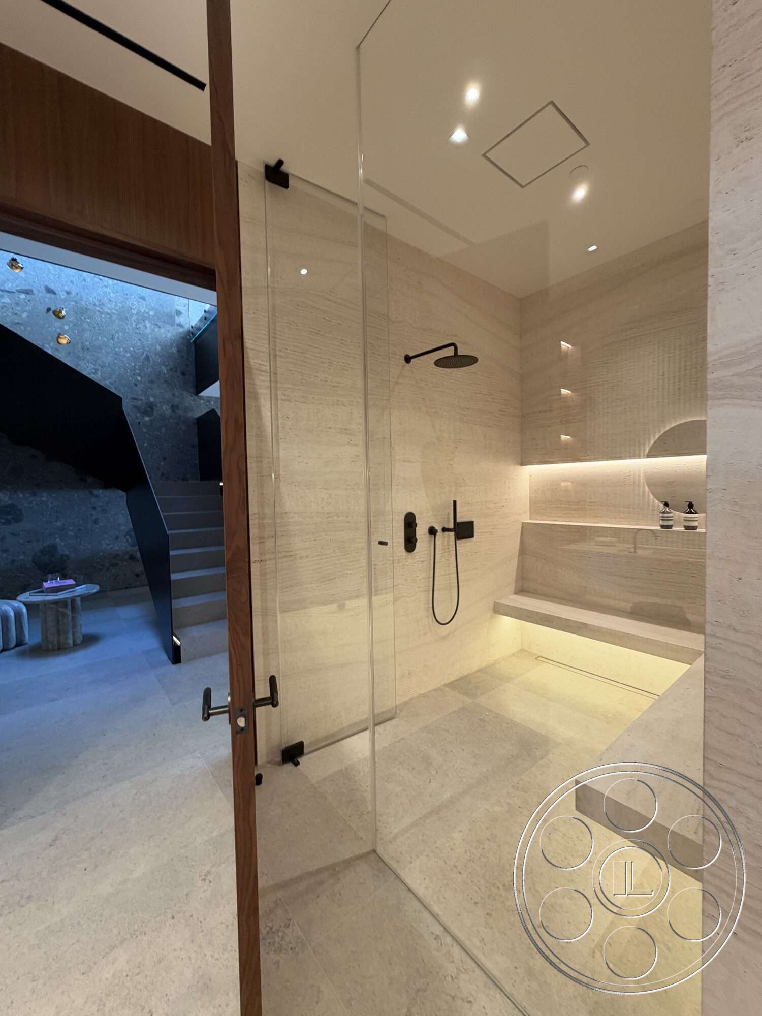 Modern 532 - neutral color palette, minimalist design, textured stone wall, wood door, recessed ceiling lights, open shower design, stone bathroom flooring, black shower fixtures, glass shower walls, floating bench
