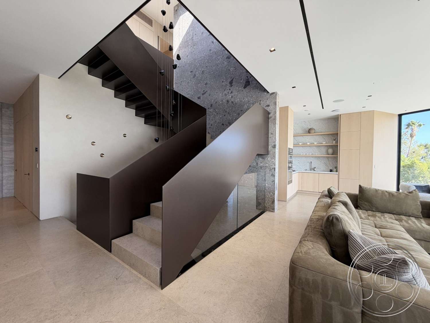 Modern 532 - natural stone flooring, large floor-to-ceiling windows, textured concrete accent wall, soft beige sectional sofa, built-in wooden kitchen cabinets, stainless steel floating staircase, modern open concept living space, under-stair storage space, minimalist ceiling lighting fixtures