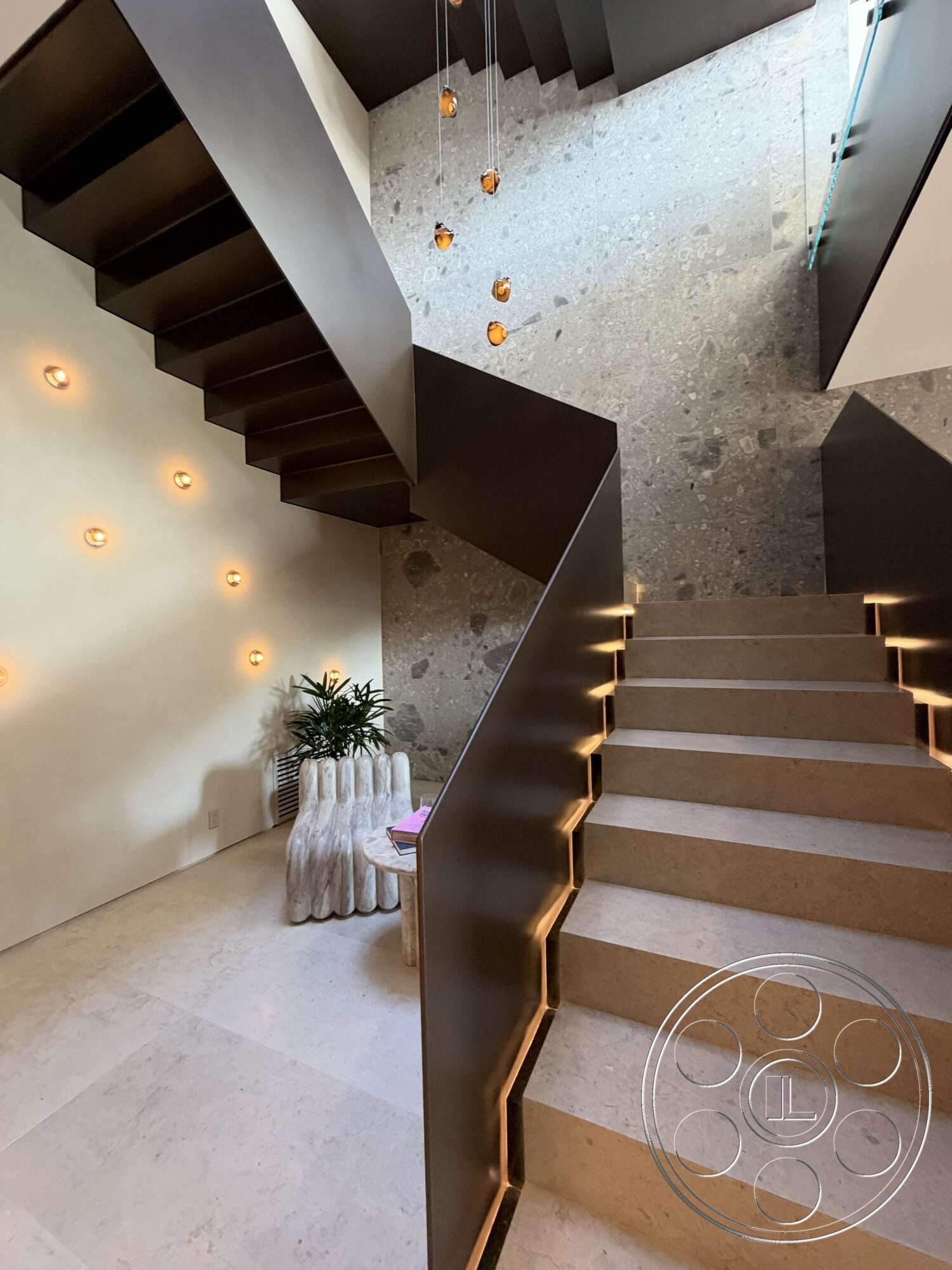 Modern 532 - modern pendant lighting, minimalist furniture, contemporary design elements, cream-colored walls, neutral stone flooring, textured stone accent wall, black metal stair railings, indoor plant display, open staircase with floating steps, architectural feature lighting