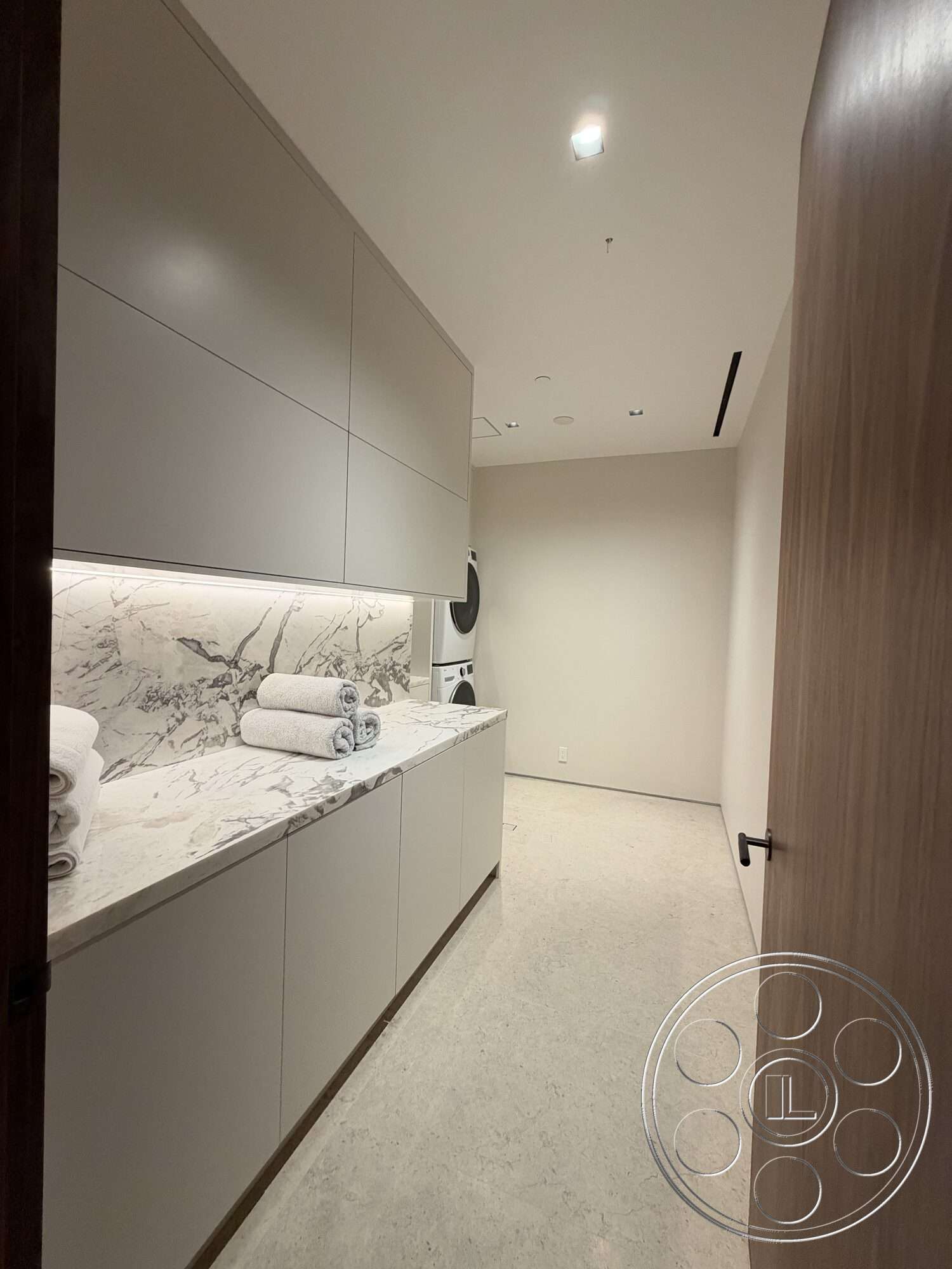 Modern 532 - modern design, concrete flooring, minimalist style, wooden door, white cabinetry, neutral wall color, marble countertop, textured stone backsplash, washer and dryer area, LED recessed lighting, soft towel linens