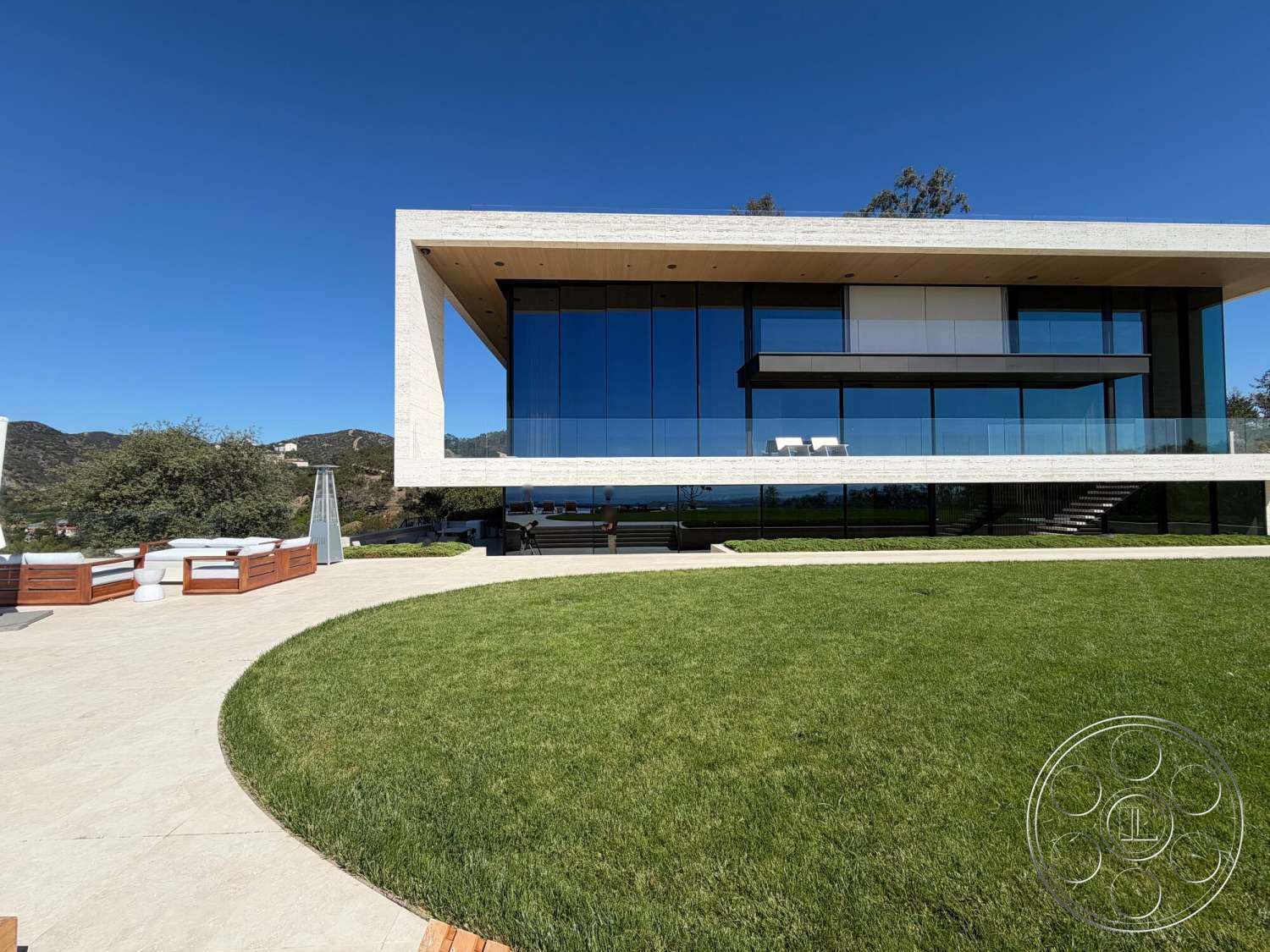 CK Mansion - exterior, modern architecture, large glass windows, concrete pathway, concrete facade, mountain view setting, landscaped grass lawn, steel railing balcony, wood ceiling overhang, rectangular stone patio, infinity edge design