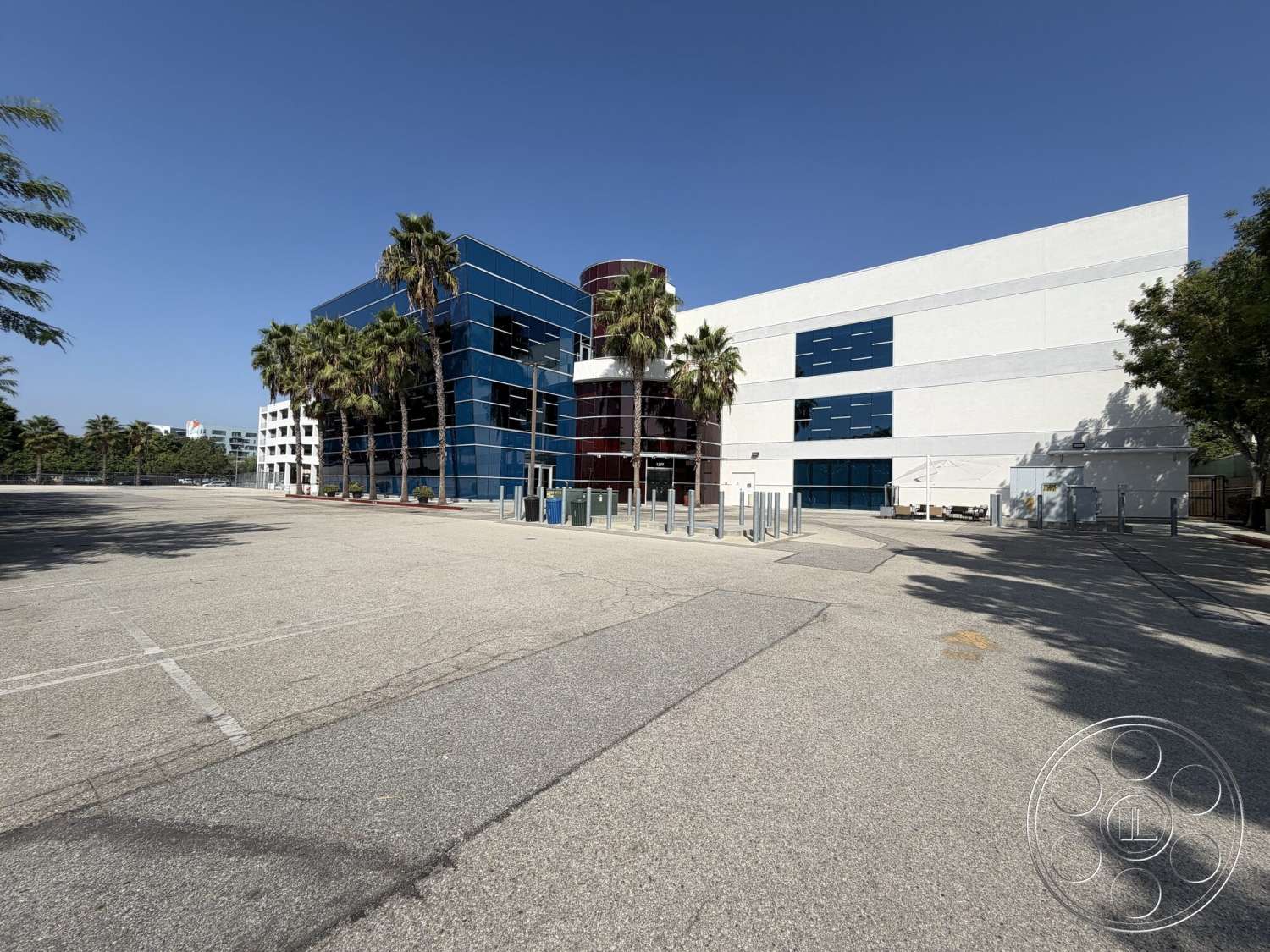 Office 130 - exterior, metal accents, urban setting, glass facade, plastered white walls, concrete parking lot, curved architectural forms, modern commercial building, landscaped palm trees, blue reflective windows