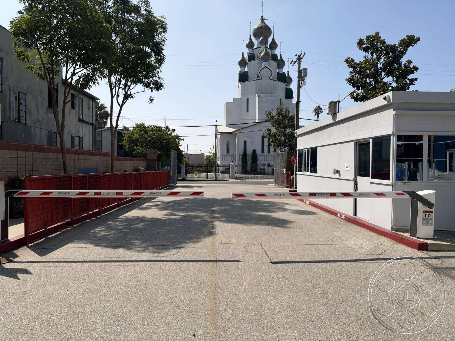 Office 130 - exterior, landscaped surroundings, surrounding trees, urban setting, commercial building, asphalt driveway, concrete barrier gate, striped security gate, monumental religious architecture, onion dome roof design, tall decorative spires, stucco church facade, low decorative wall, modern security kiosk