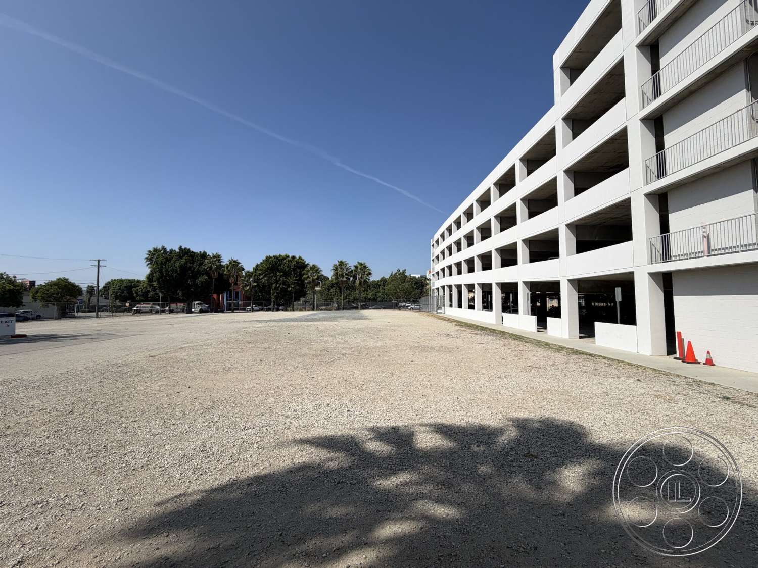 Office 130 - exterior, metal railings, urban setting, tropical landscaping, white concrete walls, flat roof design, minimalist architectural style, concrete parking structure, column-supported structure, open air parking spaces, gravel parking surface