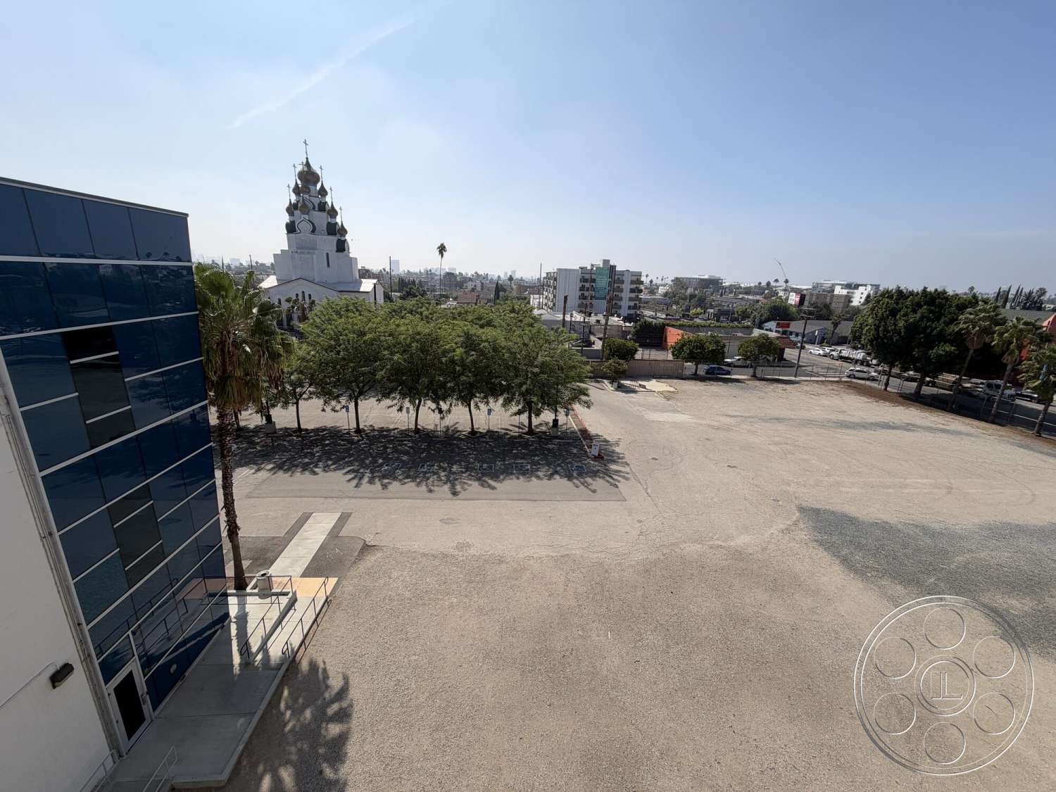 Office 130 - exterior, modern architecture, outdoor seating area, city skyline view, paved parking lot, palm trees landscaping, glass curtain wall, concrete entry steps, granite walkways