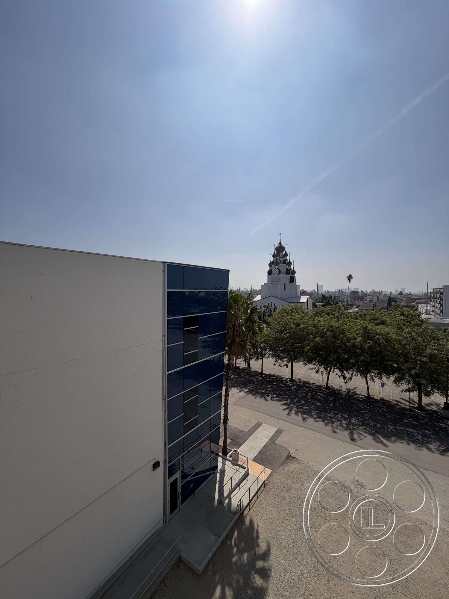 Office 130 - flat roof, urban environment, steel railing, gated entry, surrounding palm trees, concrete exterior walls, modern architectural design, rectangular building shape, city view setting, glass panel windows, minimalist entrance steps