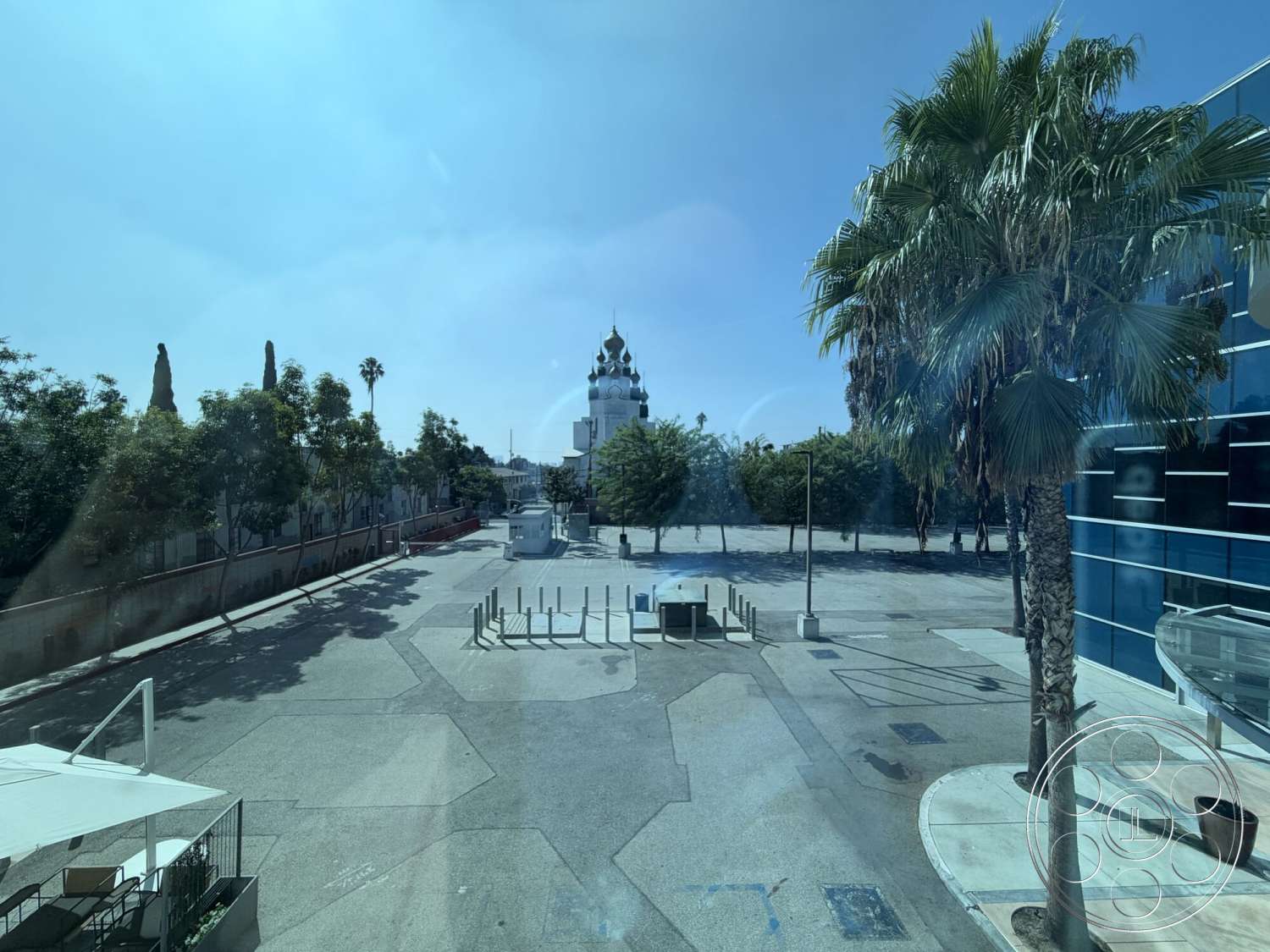 Office 130 - exterior, palm trees, outdoor seating area, concrete pavement, urban setting, tree-lined street, skyline view, blue glass facade, paved plaza, ornate building with dome