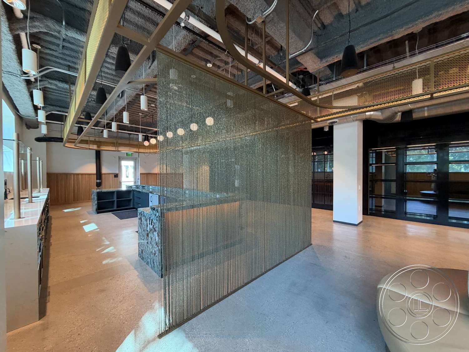 Office 130 - open floor plan, multi-functional space, concrete flooring, exposed ductwork, marble reception desk, modern industrial design, large windows with natural light, wood panel accent wall, LED pendant lighting, textured acoustic ceiling, gold metal chain partition