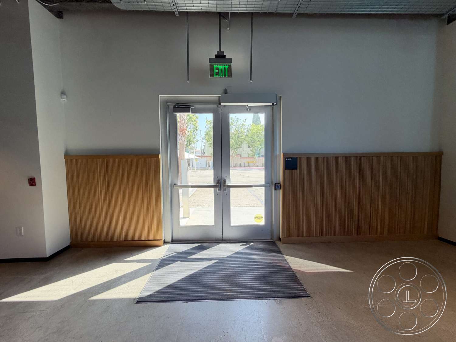 Office 130 - polished concrete flooring, horizontal wood slats, integrated lighting fixtures, glass entrance door, smooth plaster walls, metal door handle, vintage wood paneling wall, exposed ceiling with metal grid, formal entrance space, natural light through entryway