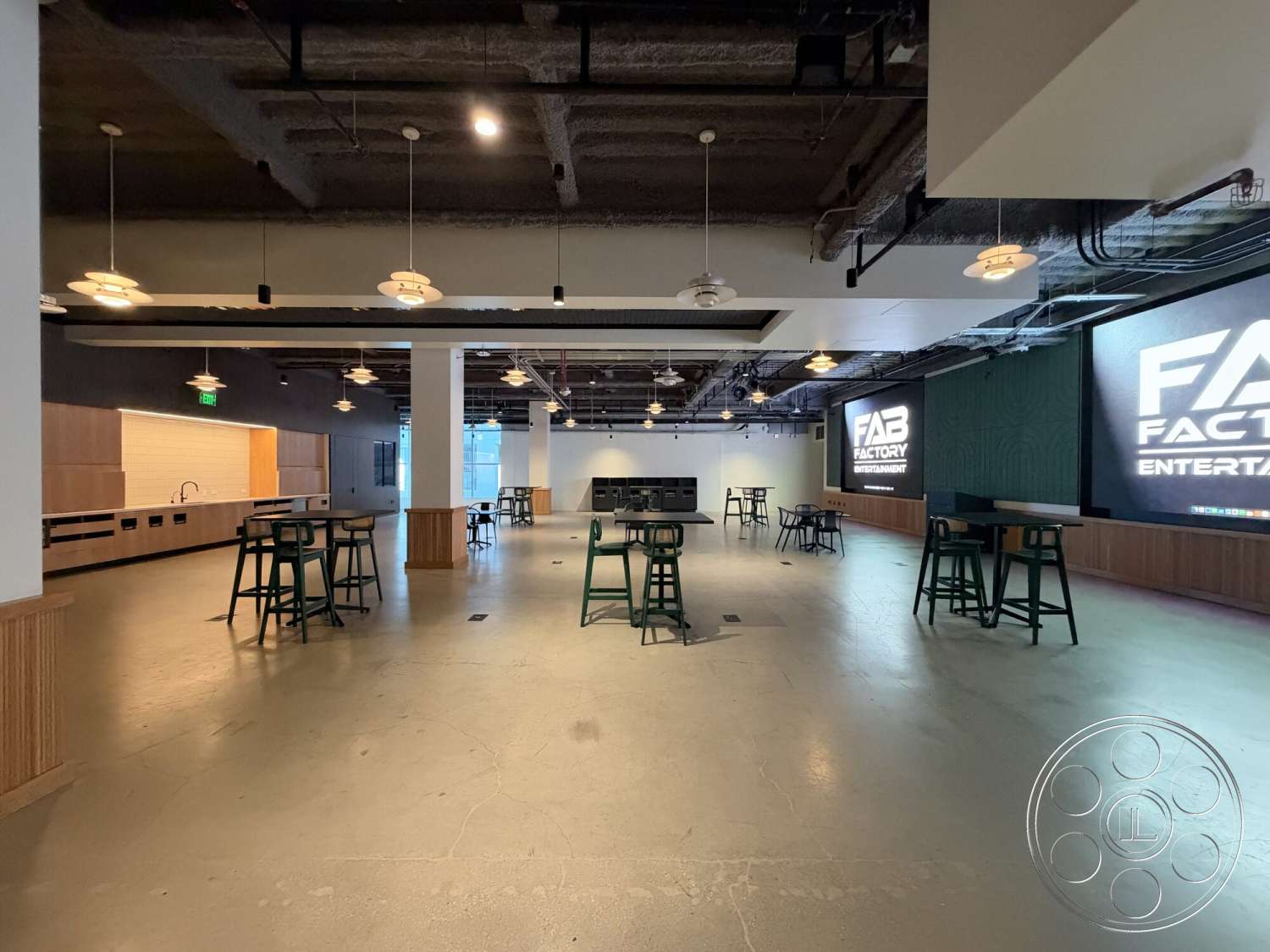 Office 130 - concrete flooring, modern lighting fixtures, industrial style, rectangular layout, wood panel accent wall, open interior space, interior entertainment area, exposed ceiling ducts, wooden bar cabinets, wall-mounted screens, walls with dark paint, outdoor view through large windows