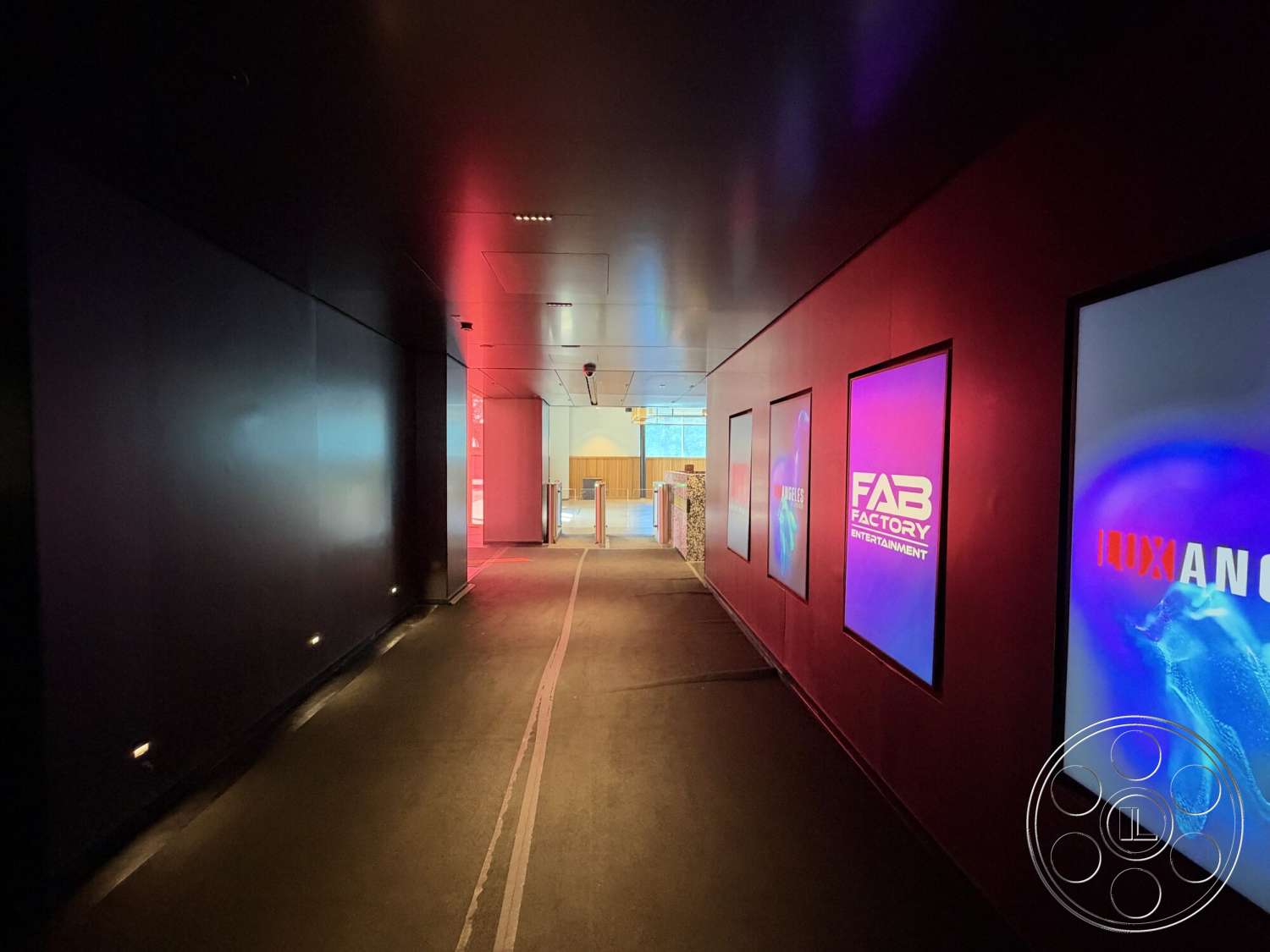 Office 130 - concrete flooring, red accent wall, open doorway, dark wood ceiling, interior hallway, linear lighting fixtures, metal wall panels, wall-mounted display screens, textured surface wall
