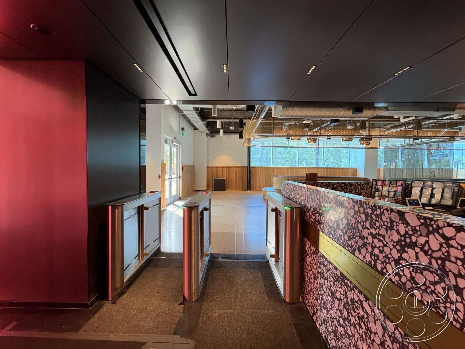 Office 130 - polished concrete flooring, floor-to-ceiling windows, exposed ductwork, white painted walls, modern reception desk, textured ceiling panels, black wall paneling, wood feature wall, metal ticket barriers, glossy ticket counter
